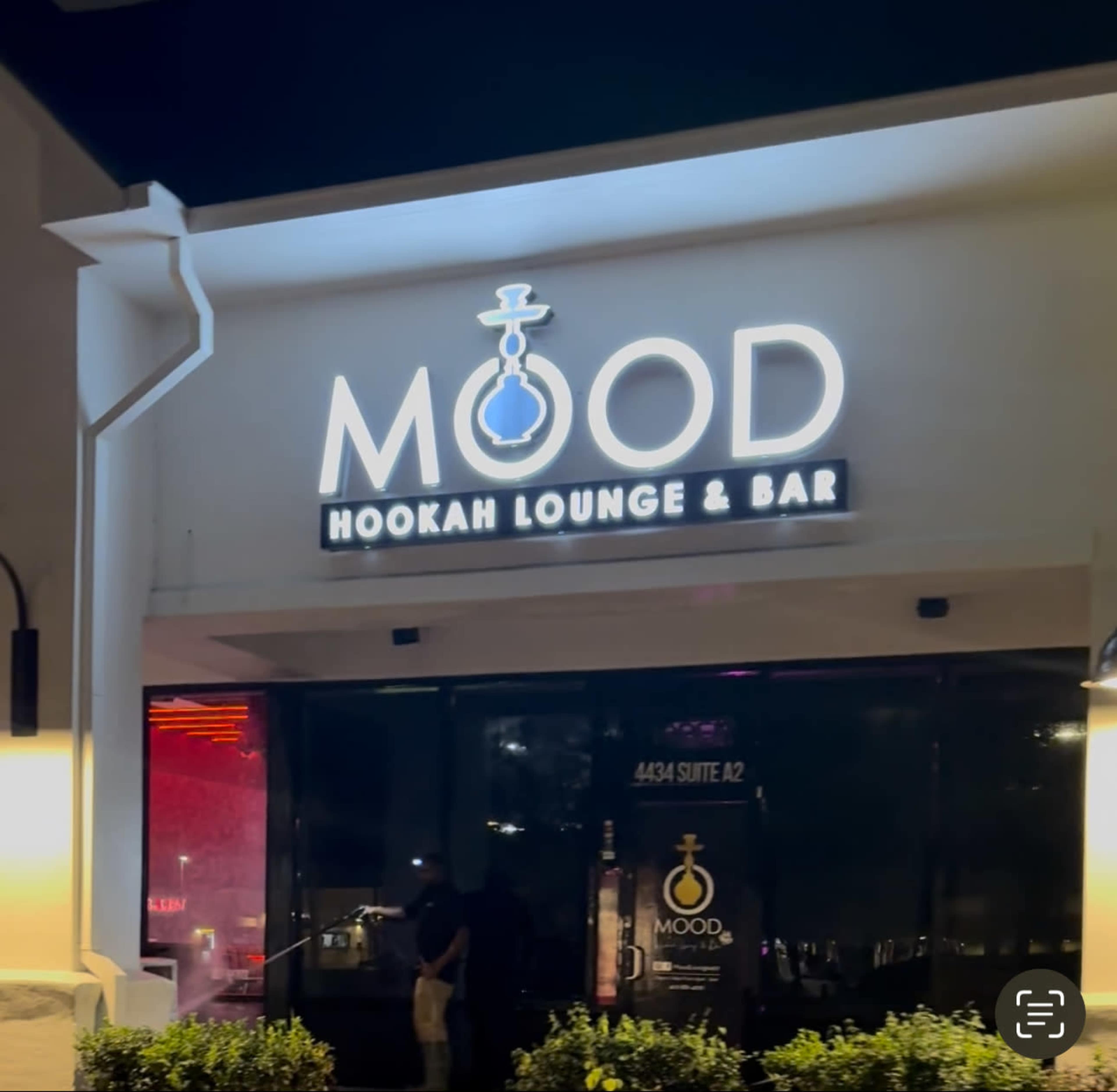 The image shows the exterior of a lounge and bar called "MOOD," featuring a sign with the words "HOOKAH LOUNGE & BAR" illuminated in lights.