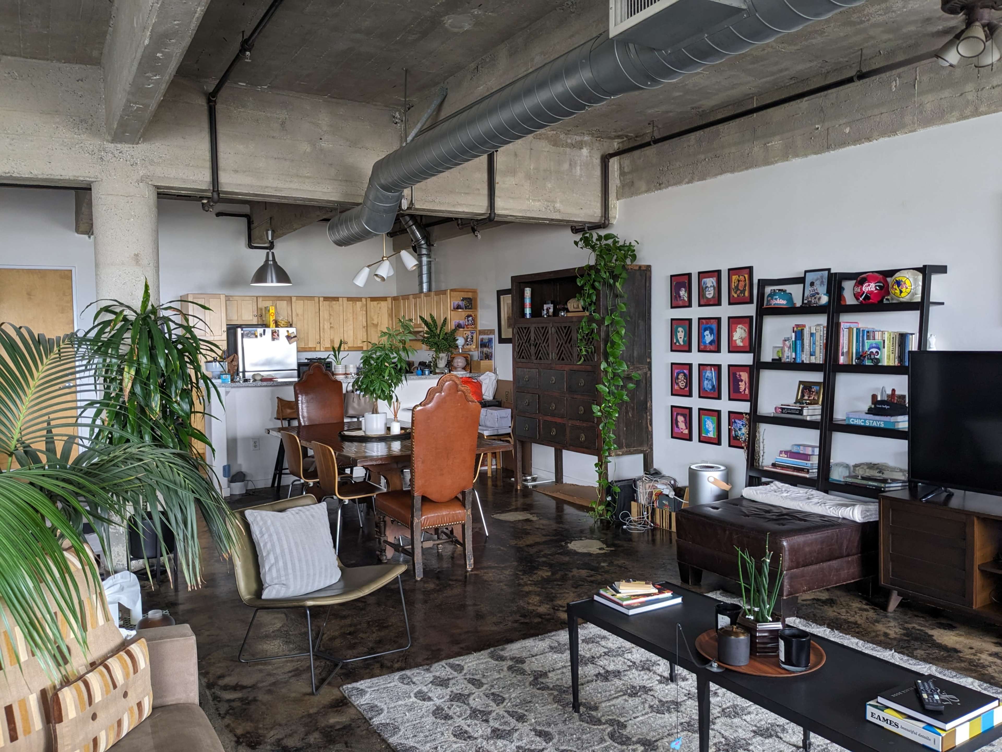 A modern industrial-style apartment with an open layout featuring a living area, dining space, and kitchen.