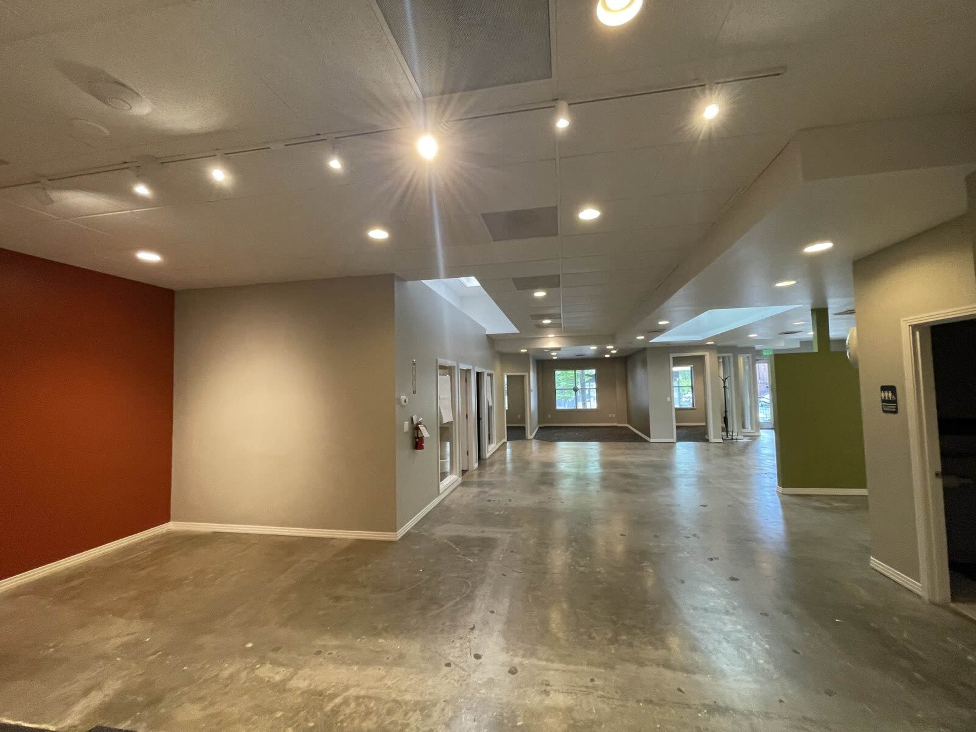 The image shows a spacious, unfinished interior of an office or commercial building with multiple doorways and a mix of wall colors.