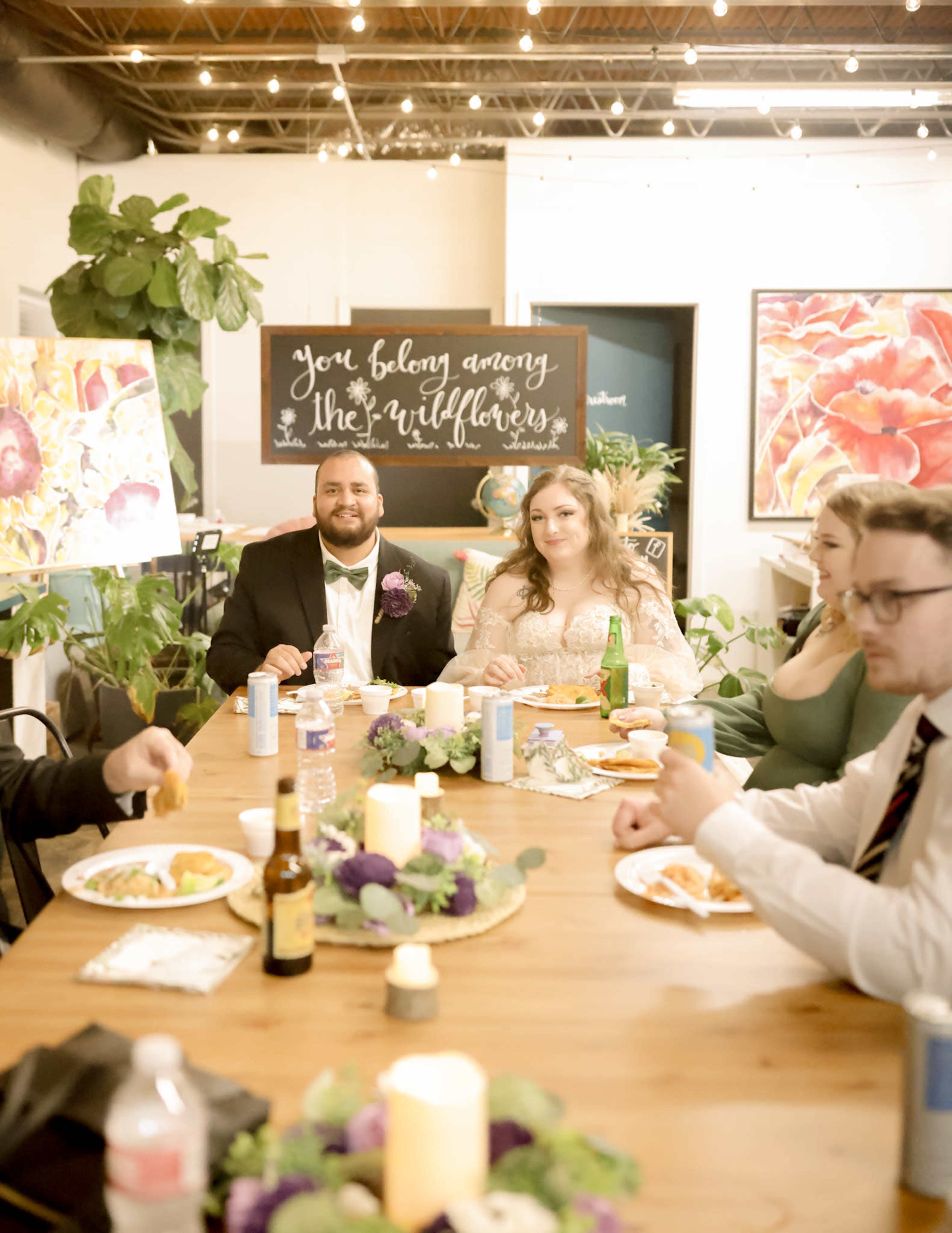A group of five people sits around a table decorated with food and drinks, enjoying a gathering in a decorated room.