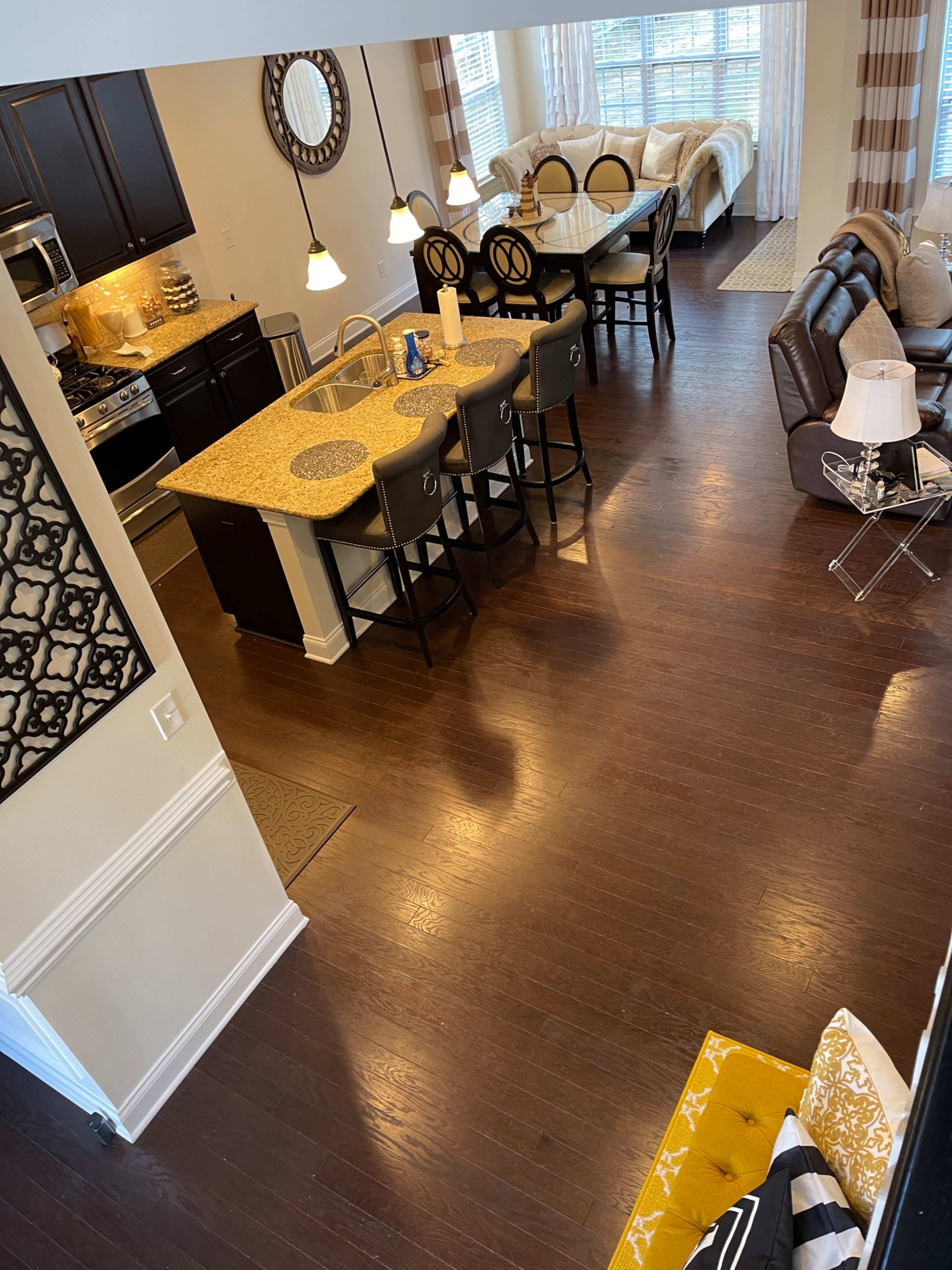 An open-concept living space featuring a kitchen with a granite island, a dining area with barstools, and a cozy seating area with a sofa and decorative pillows.