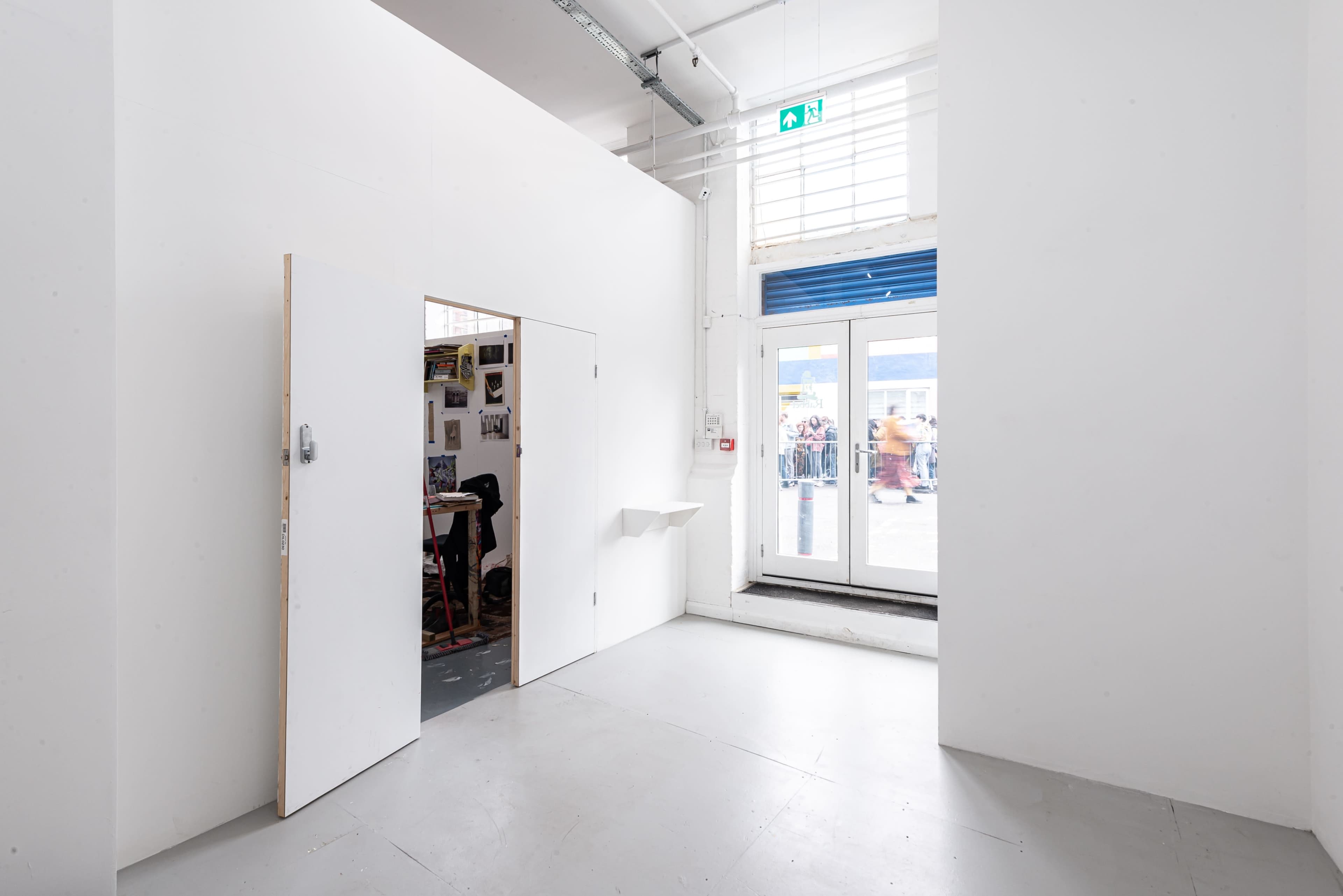 A bright, minimalistic interior space with a door on the left and a large windowed entrance on the right.