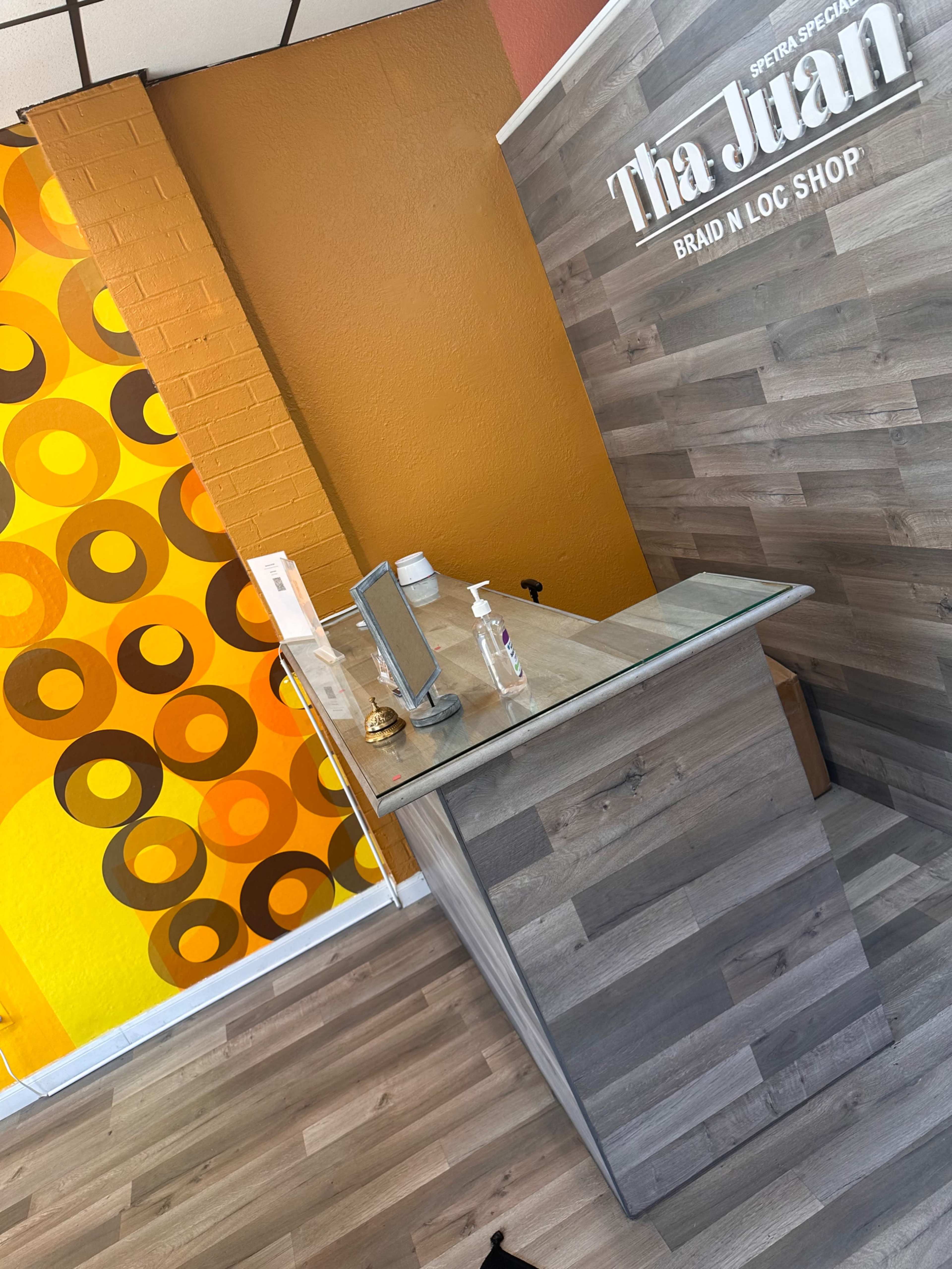 The interior of a hair salon with a modern reception desk and a colorful patterned wall featuring circles.