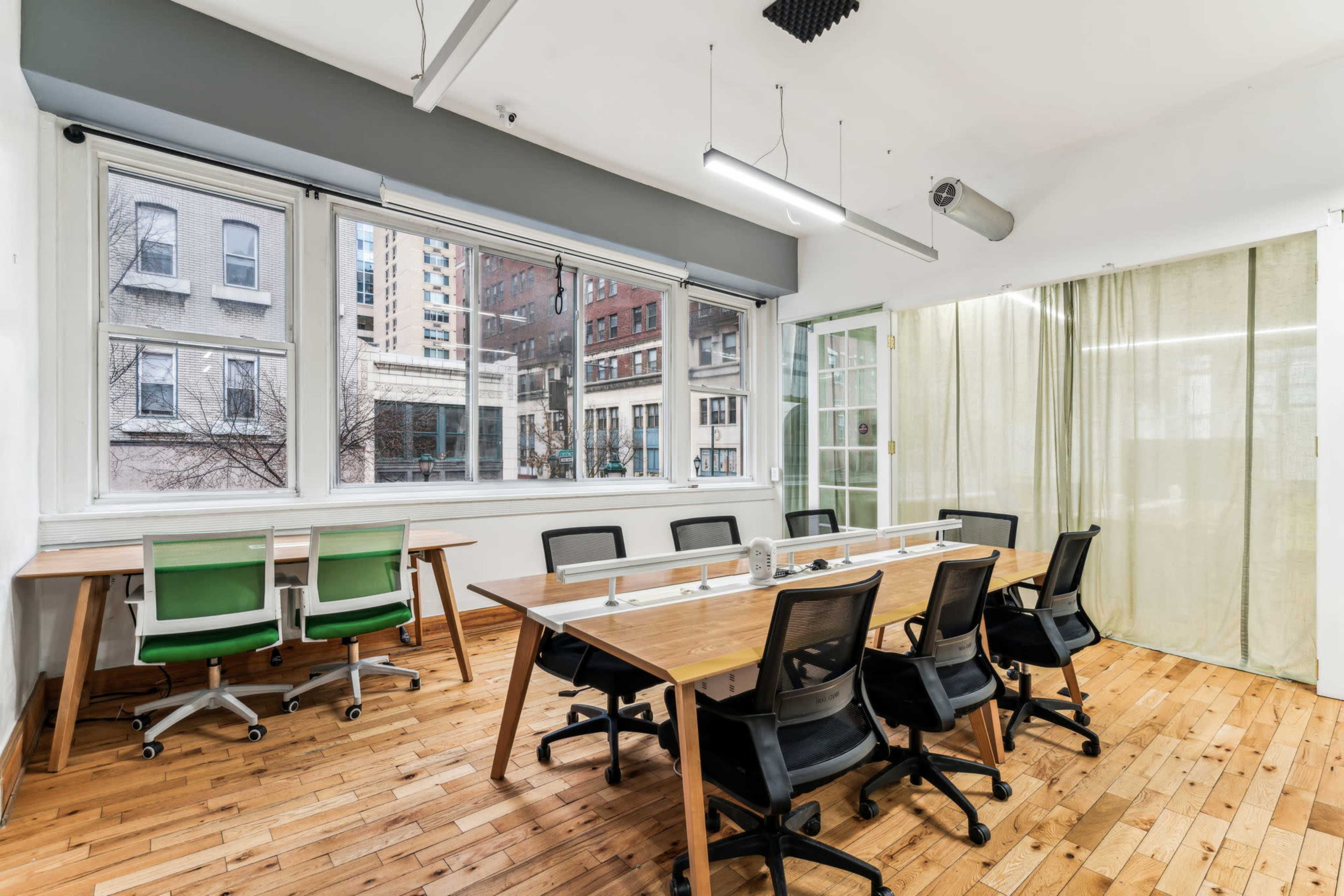 The image shows a modern conference room with a wooden table and black chairs, large windows overlooking a cityscape, and a translucent partition.