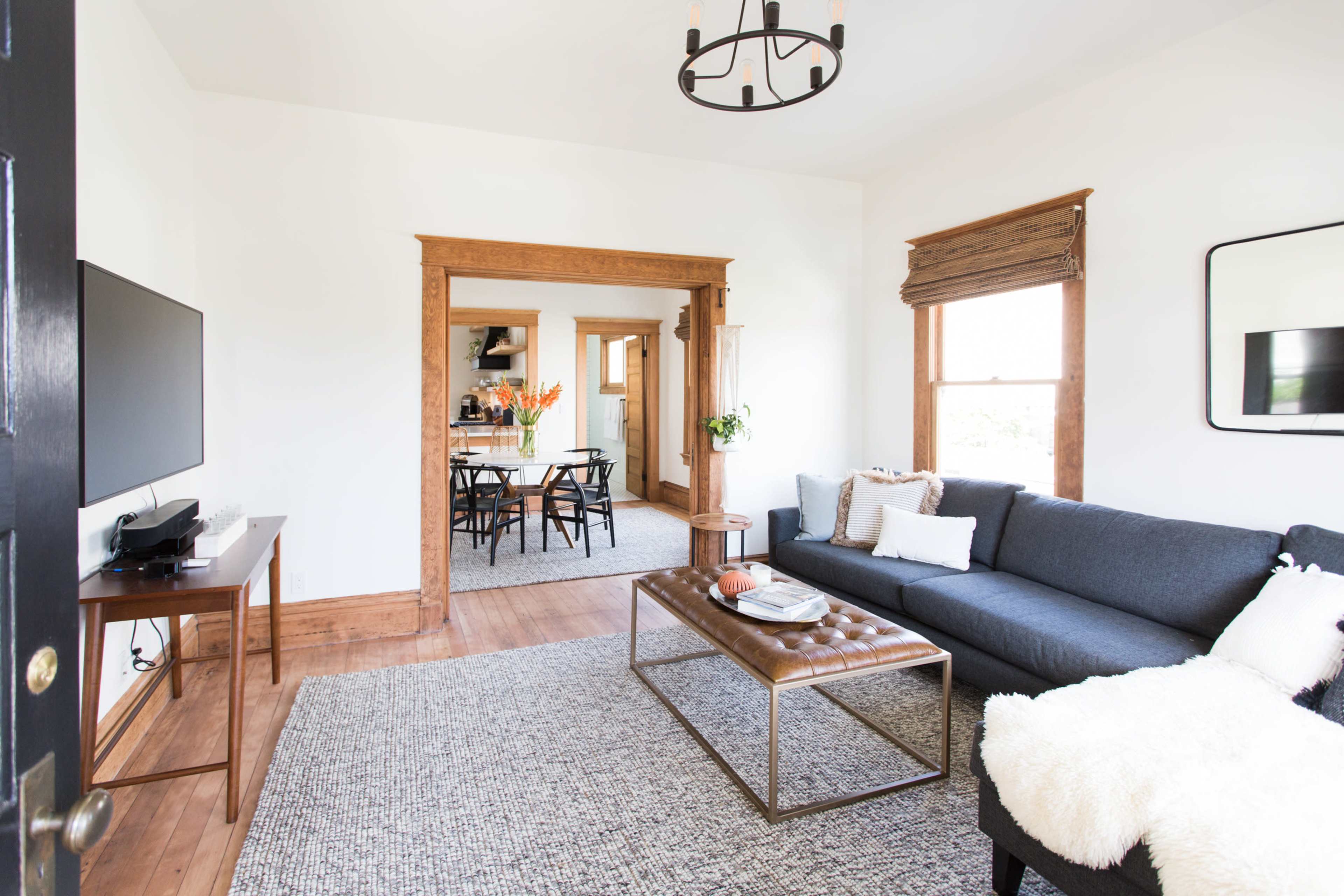 A living room with a gray sofa, a coffee table, and a view into a dining area through an archway.