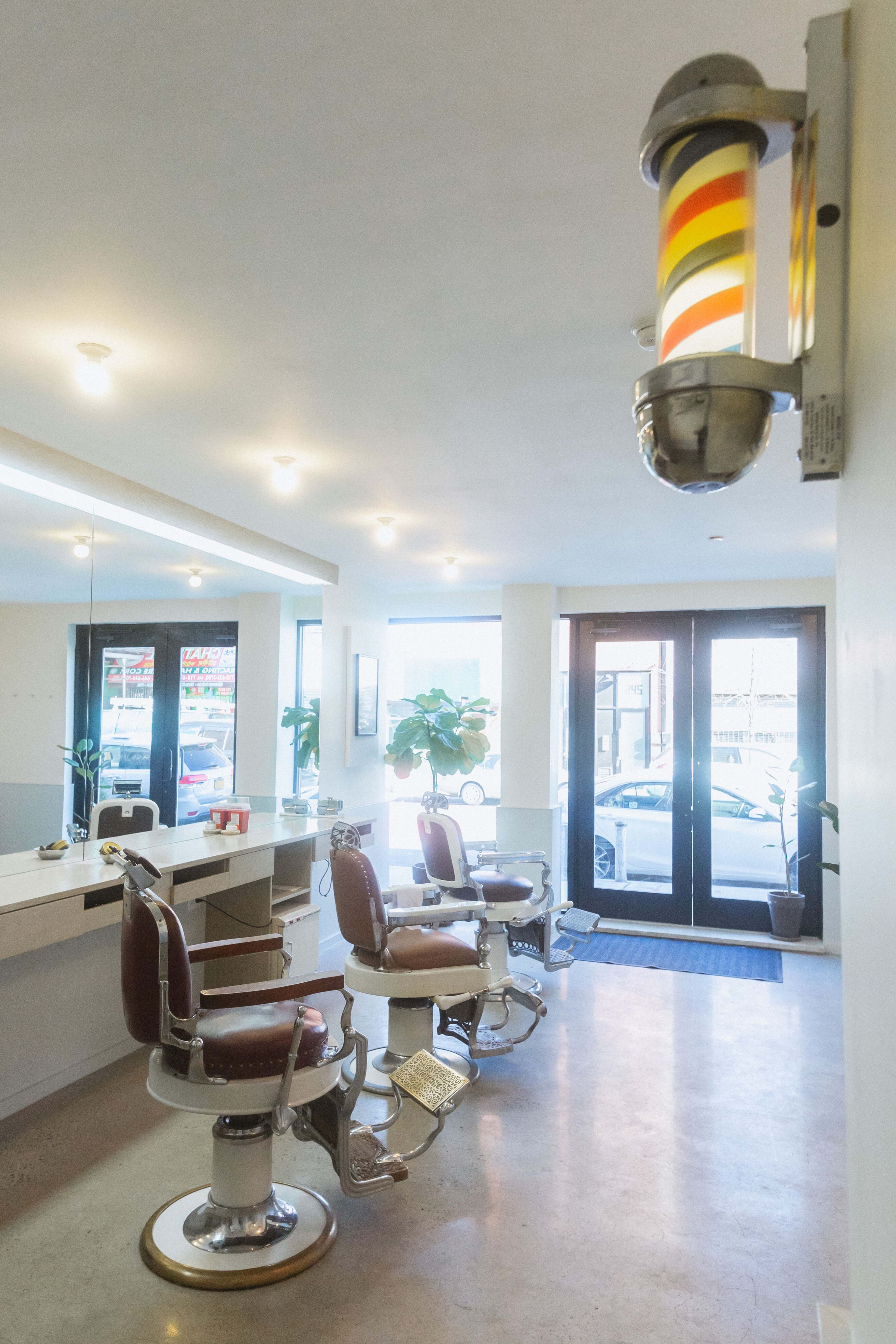 A clean barbershop interior with two barber chairs, a mirror, and a classic barber pole.