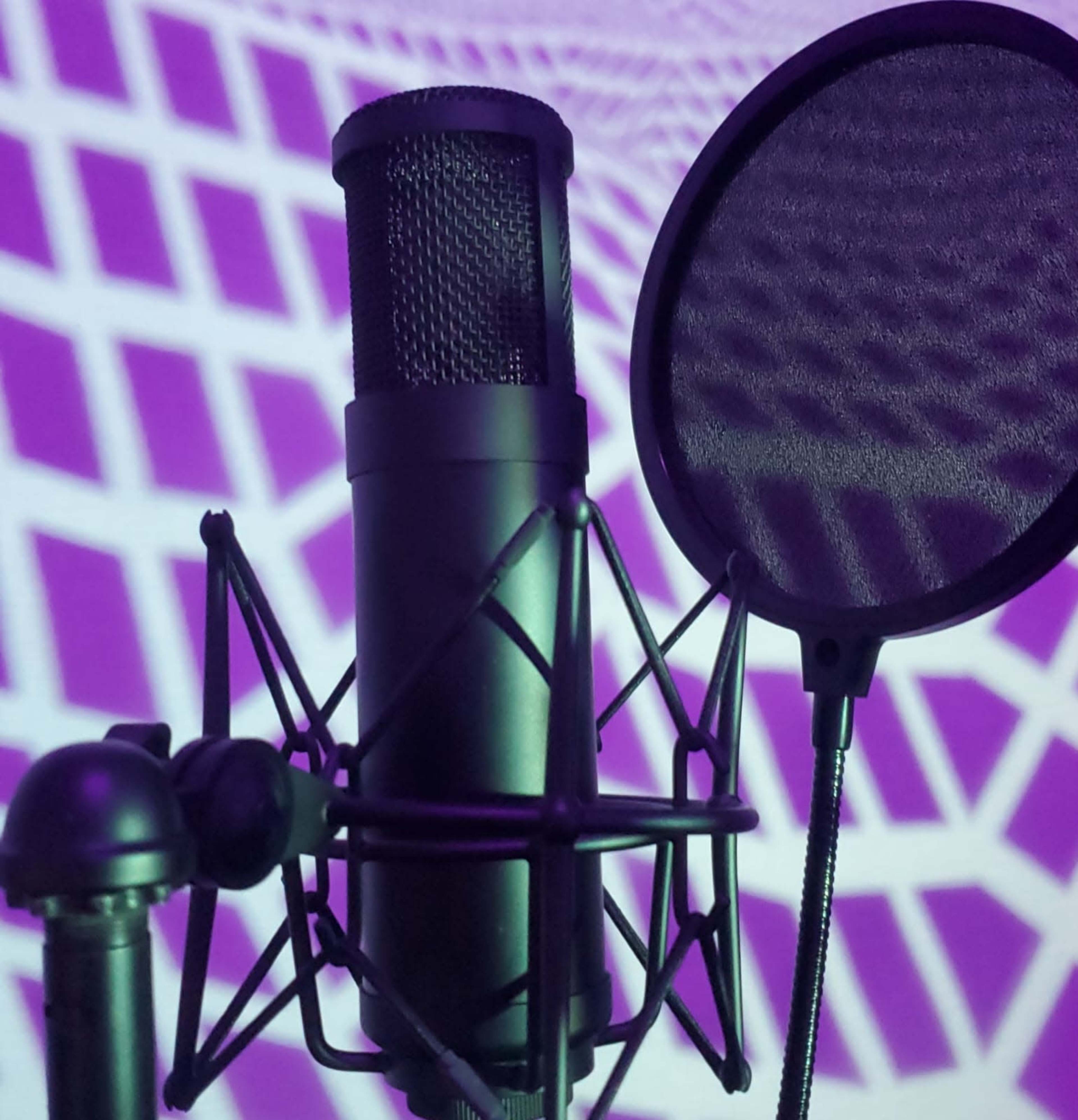 A microphone stands beside a pop filter with a purple geometric pattern projected in the background.
