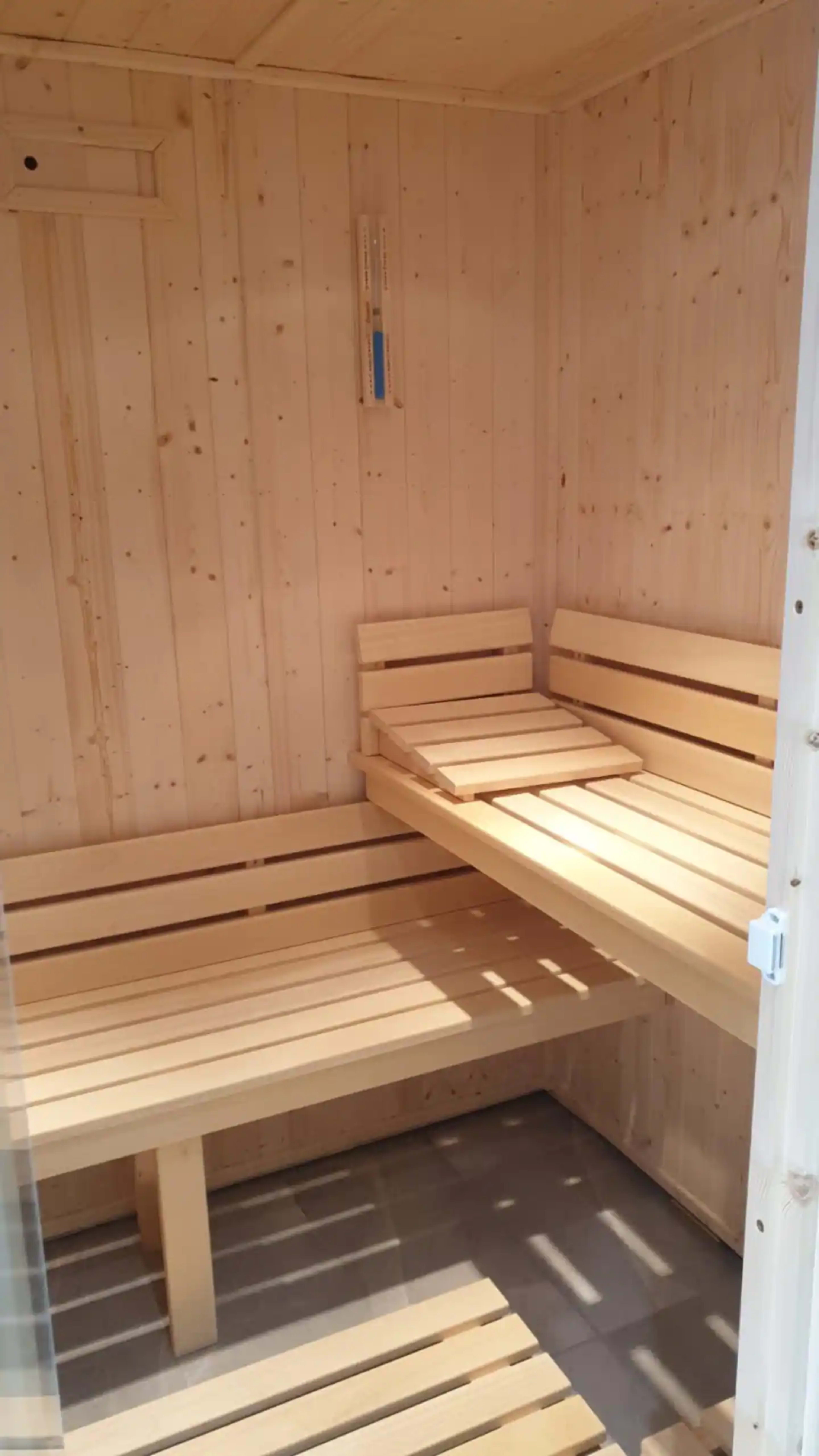 A wooden sauna interior with benches and a light-colored wooden finish.