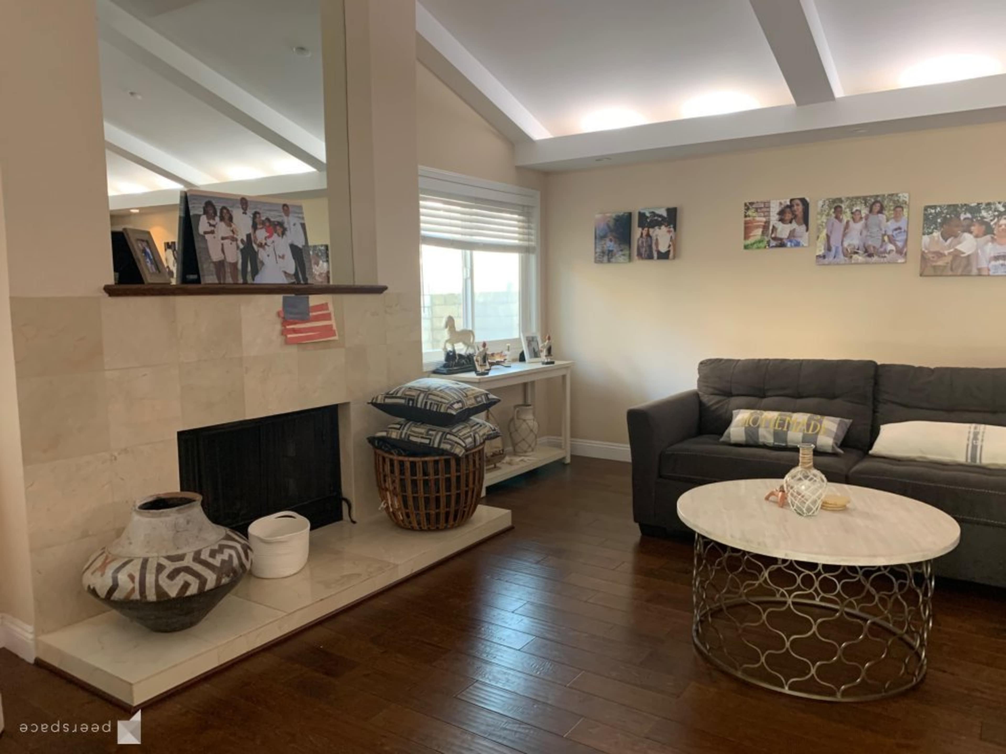 A living room with a sofa, a round coffee table, a fireplace, and family photographs displayed on the wall.