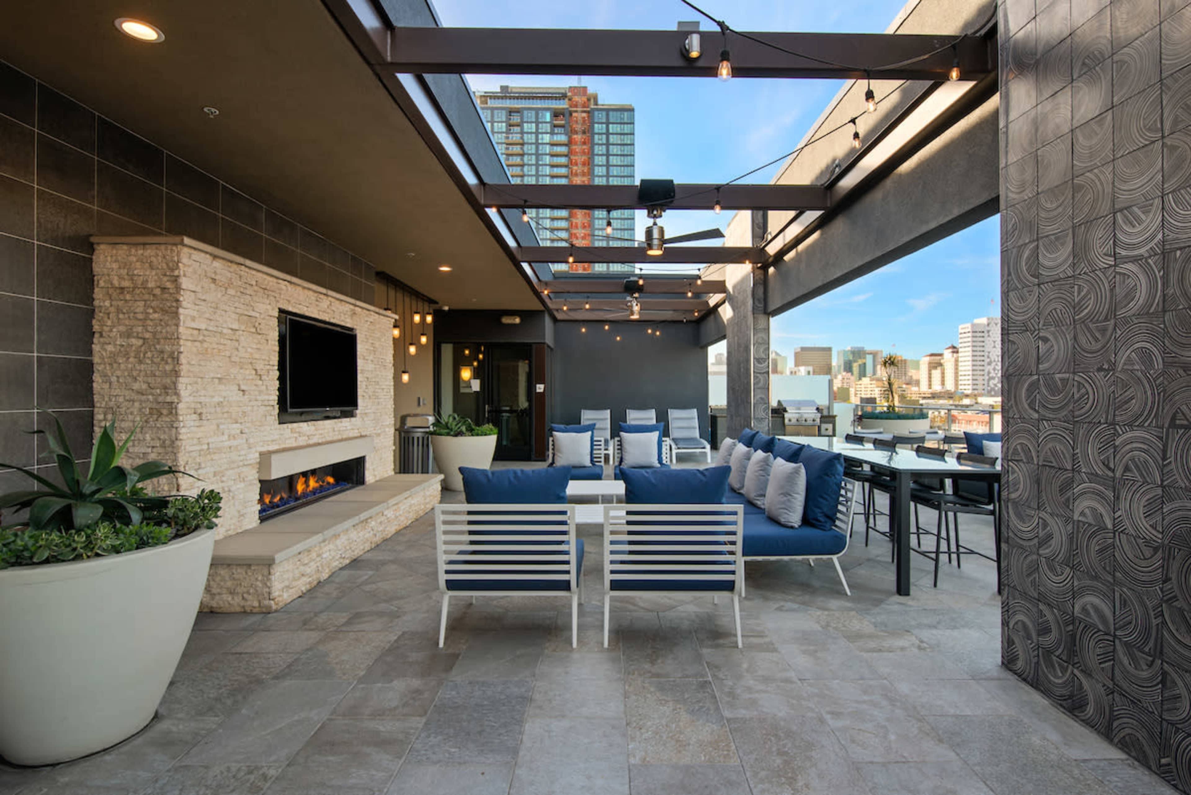 A spacious rooftop terrace with a modern seating area, an outdoor fireplace, and city views.