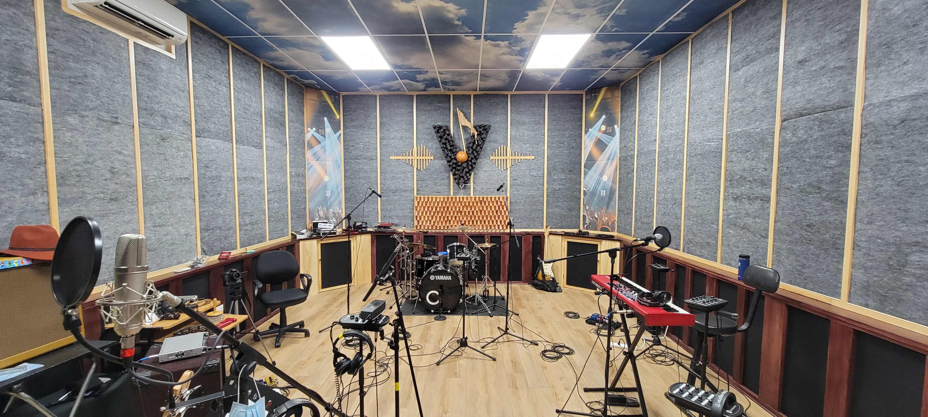 A soundproof music studio featuring various instruments, microphones, and acoustic paneling on the walls.