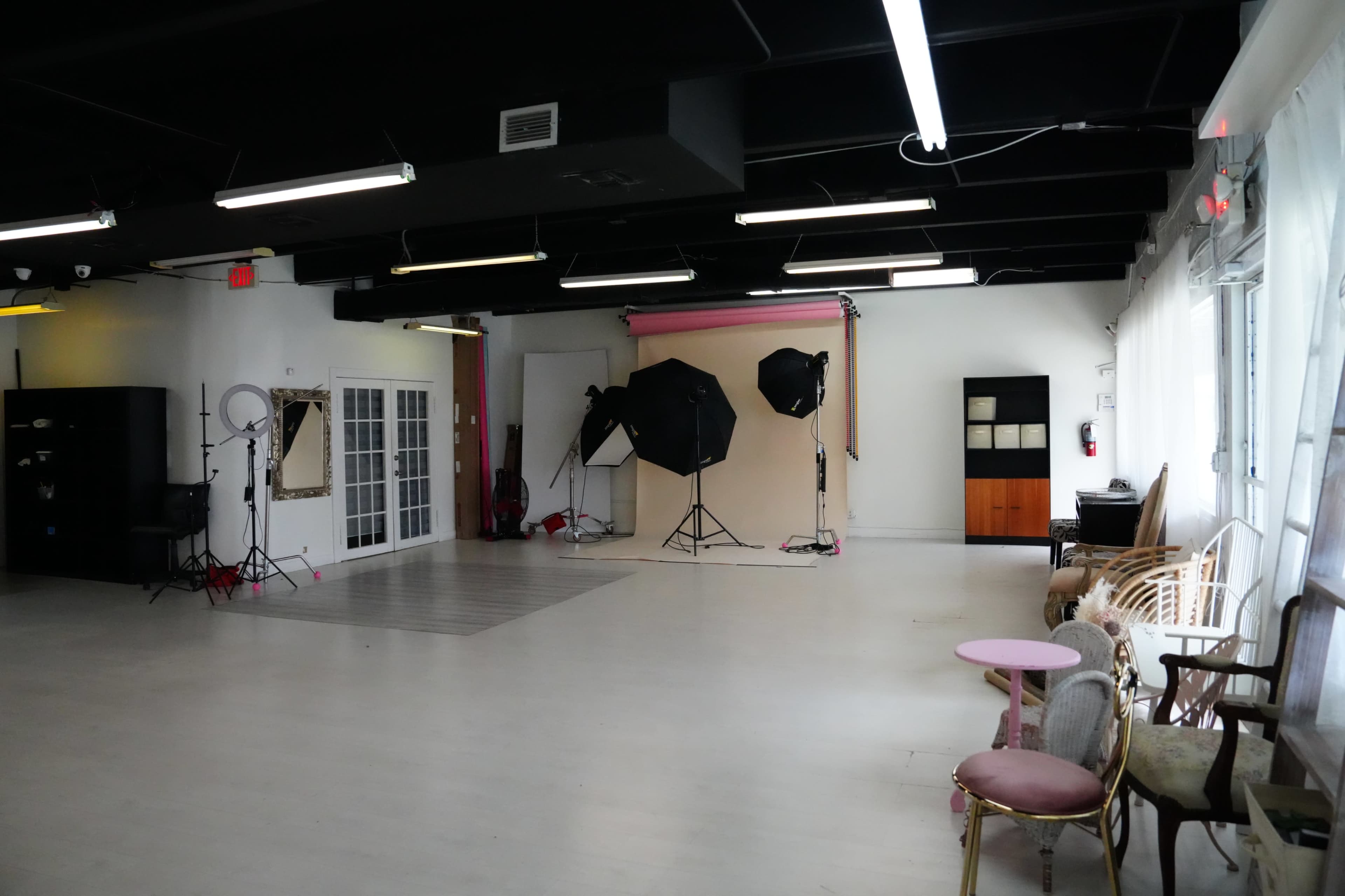 A spacious photography studio features various lighting equipment, colorful backdrops, and seating arrangements.