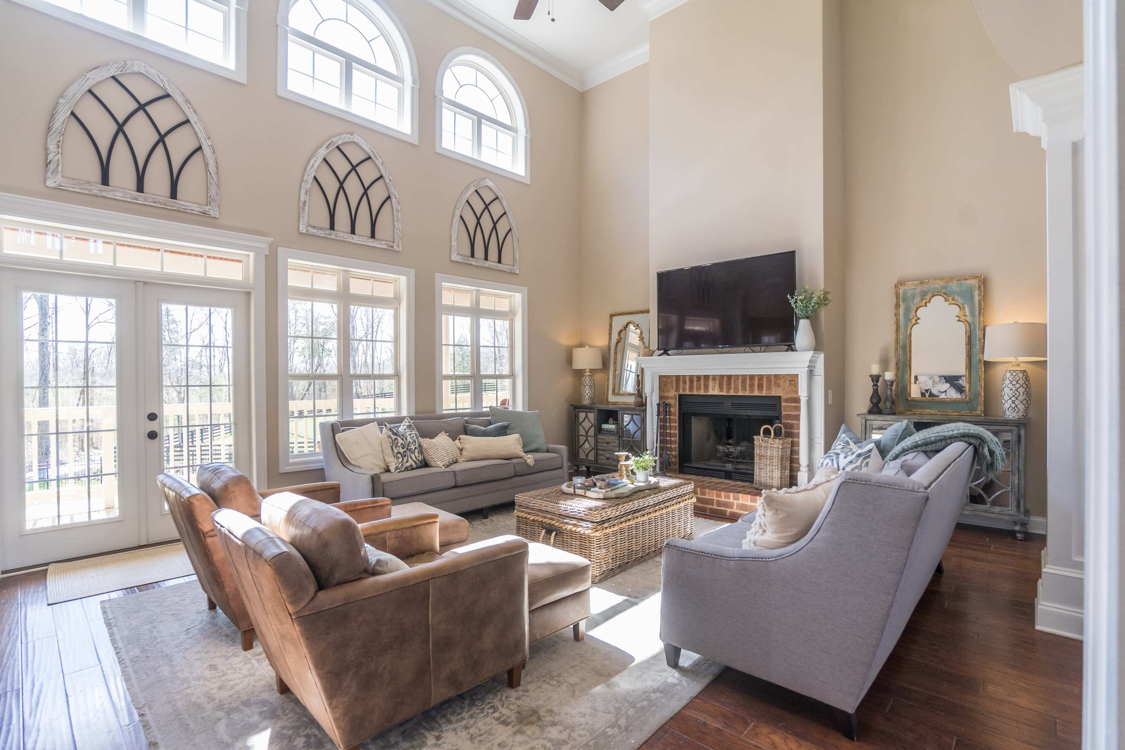 The living room features large windows, two sofas, and a fireplace with decorative elements.