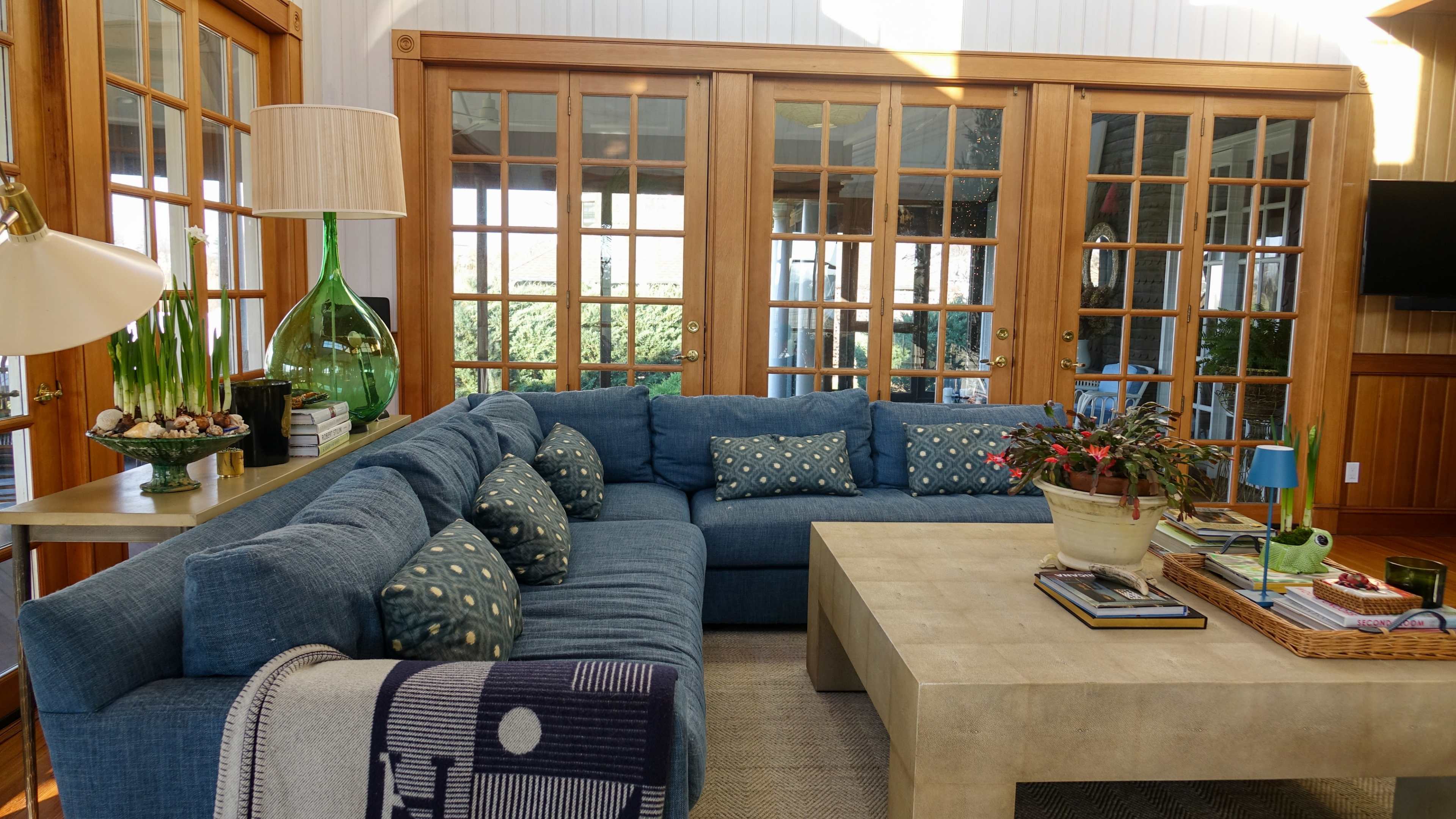 A spacious living room featuring a blue sectional sofa, a light-colored coffee table, and large glass doors leading to an outdoor area.