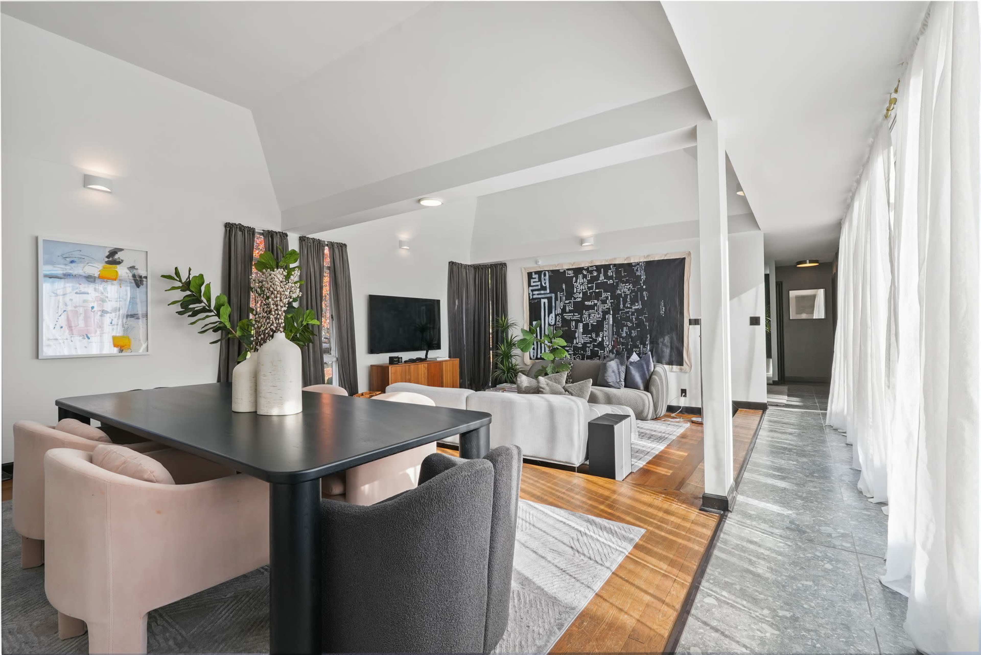A spacious living area features a dark wall mural, a dining table with chairs, and comfortable seating arranged around a television.