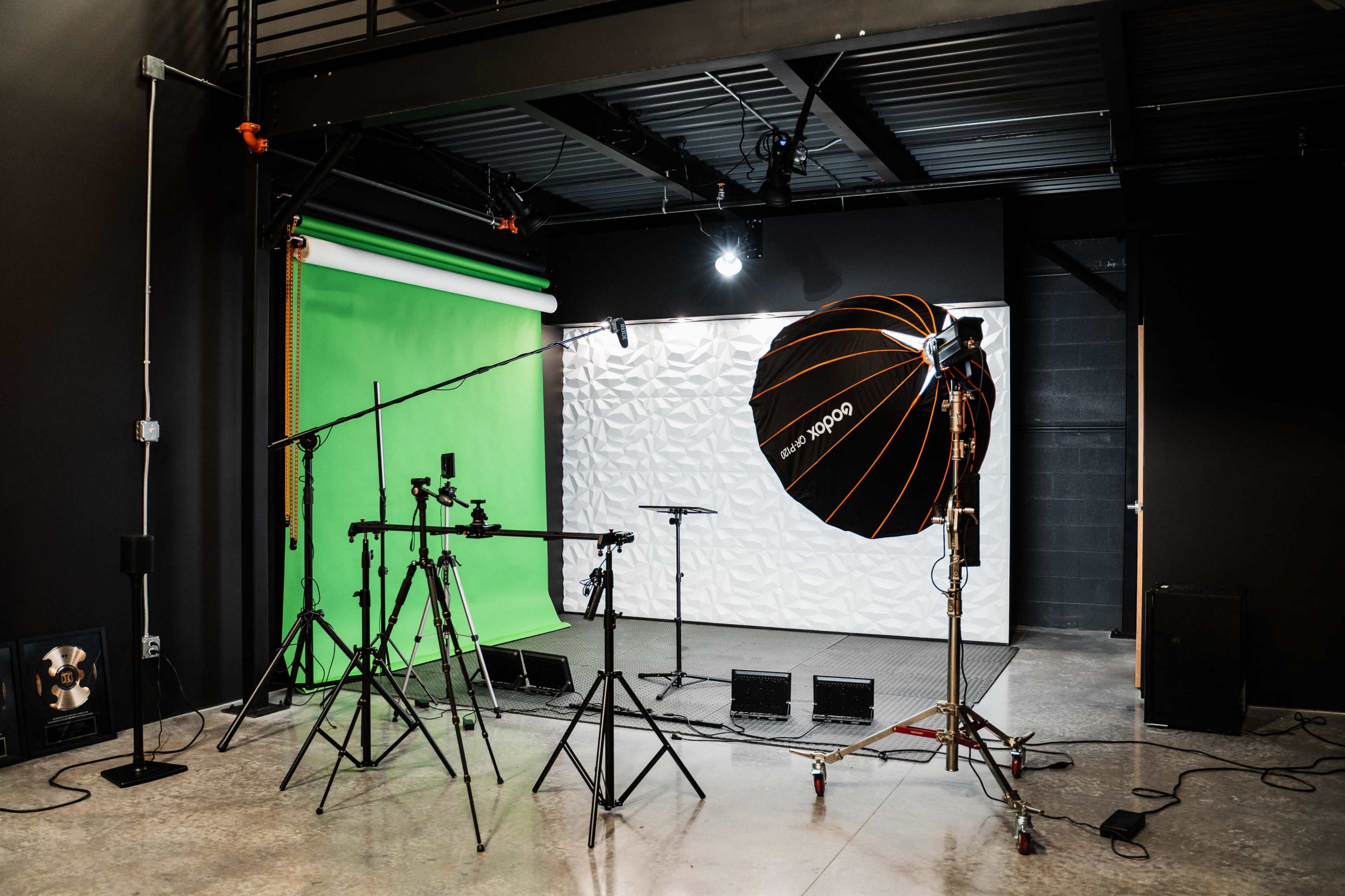 The image shows a photography studio equipped with green and textured white backdrops, lighting equipment, and tripods.