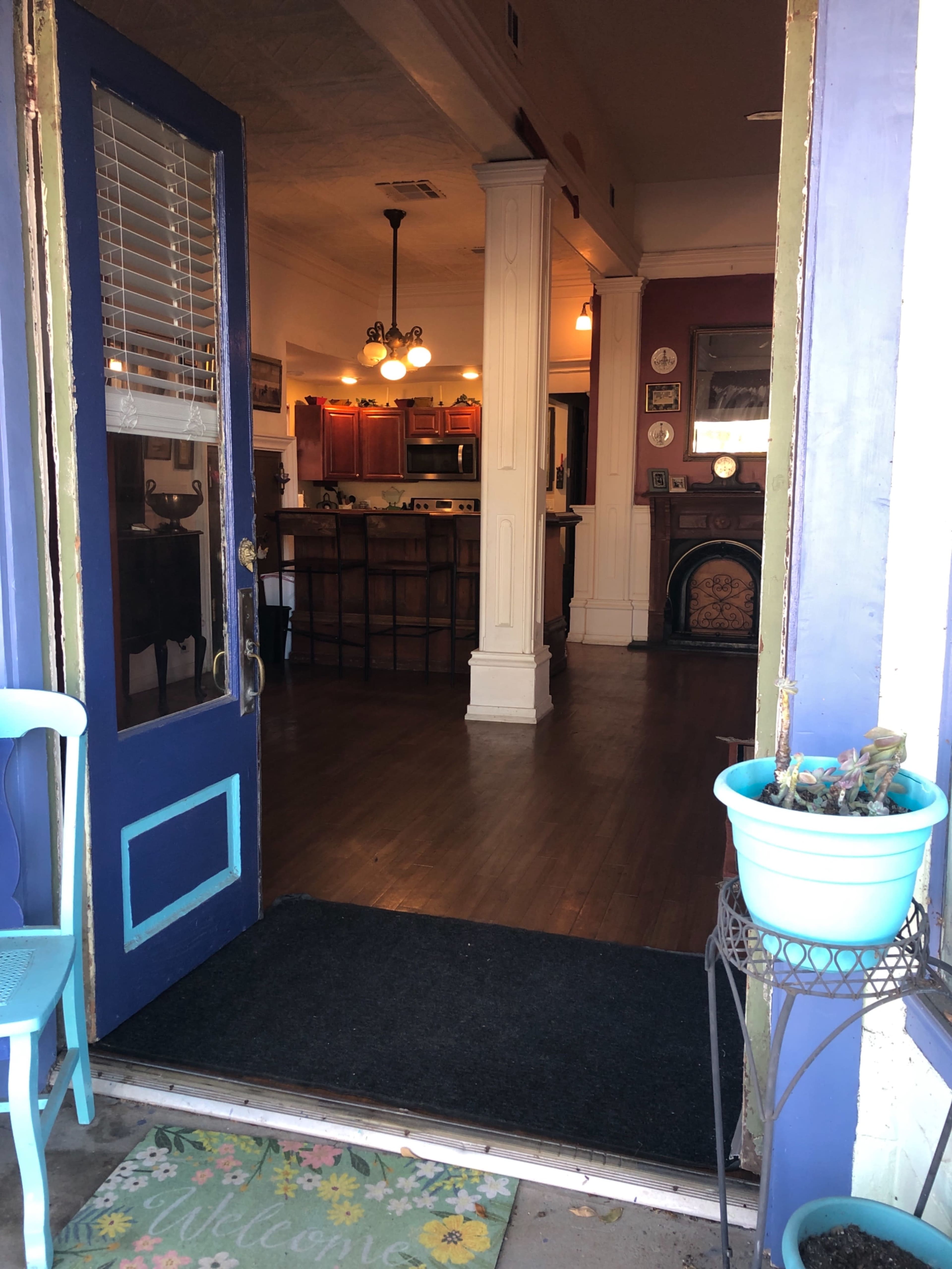 A view through a blue door leads to a cozy interior with a kitchen and dining area visible in the background.