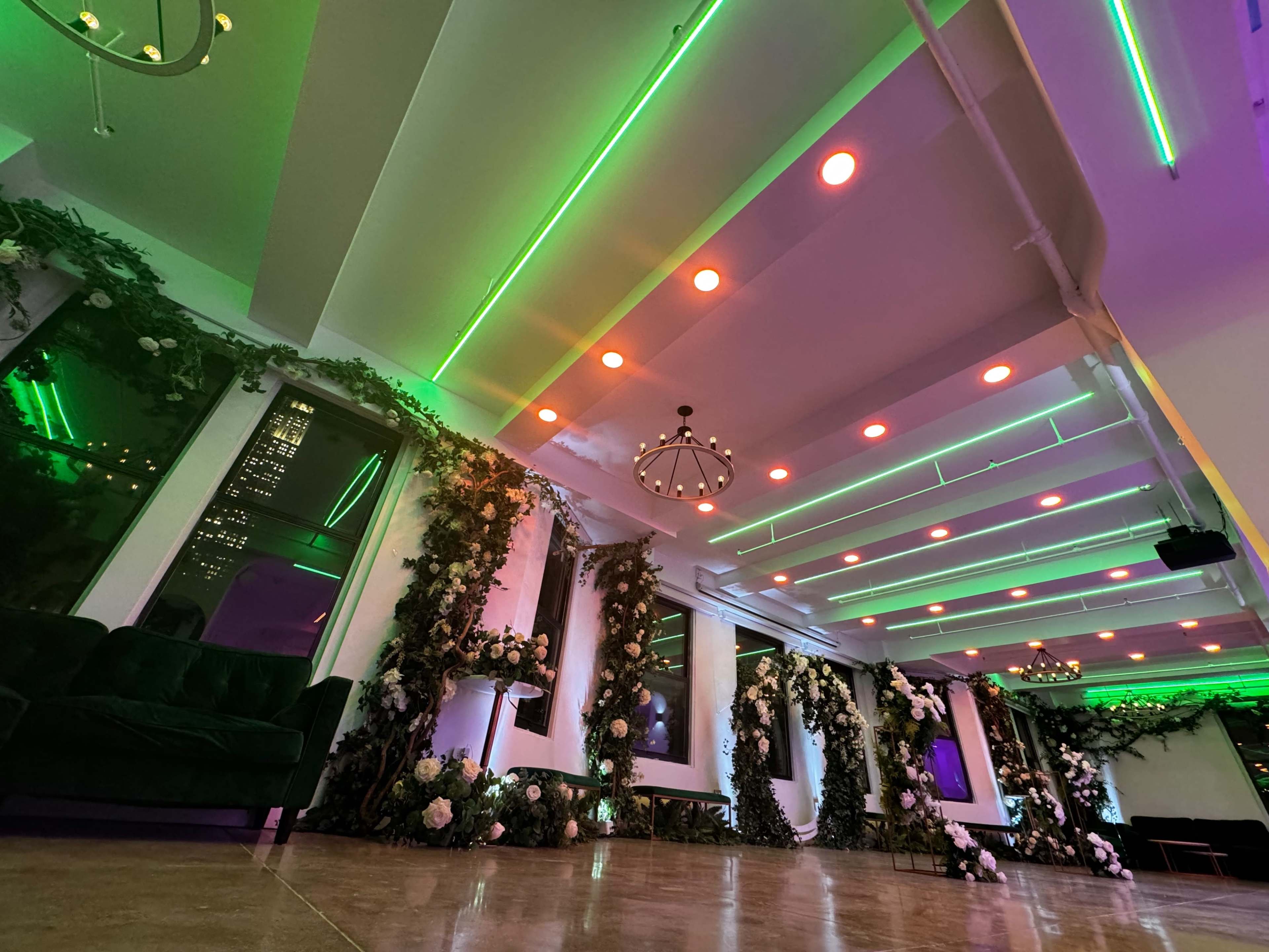 A stylish interior space with green and orange LED lights on the ceiling and floral decorations along the walls.