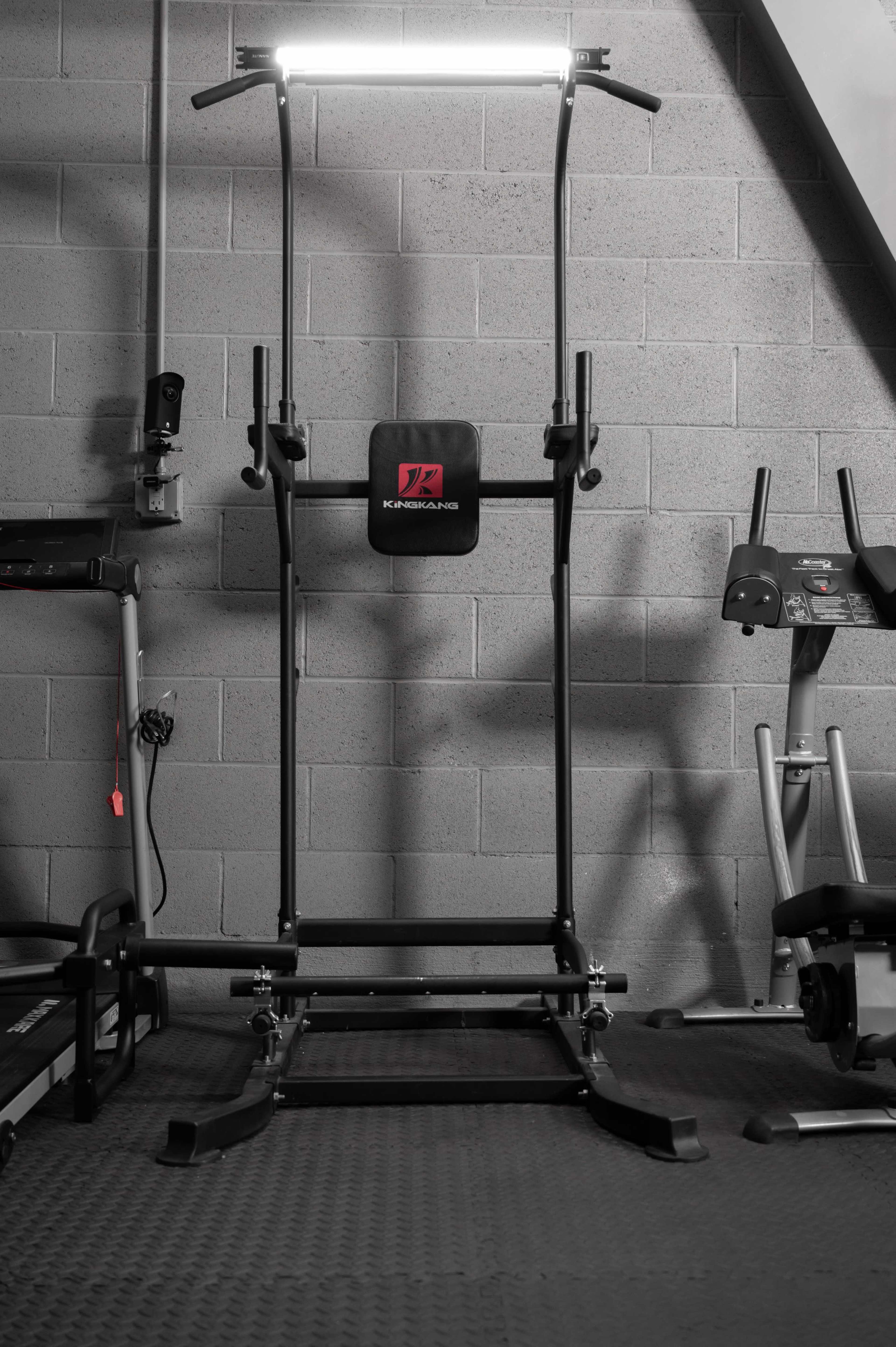 A multi-functional exercise machine set against a gray wall in a gym.