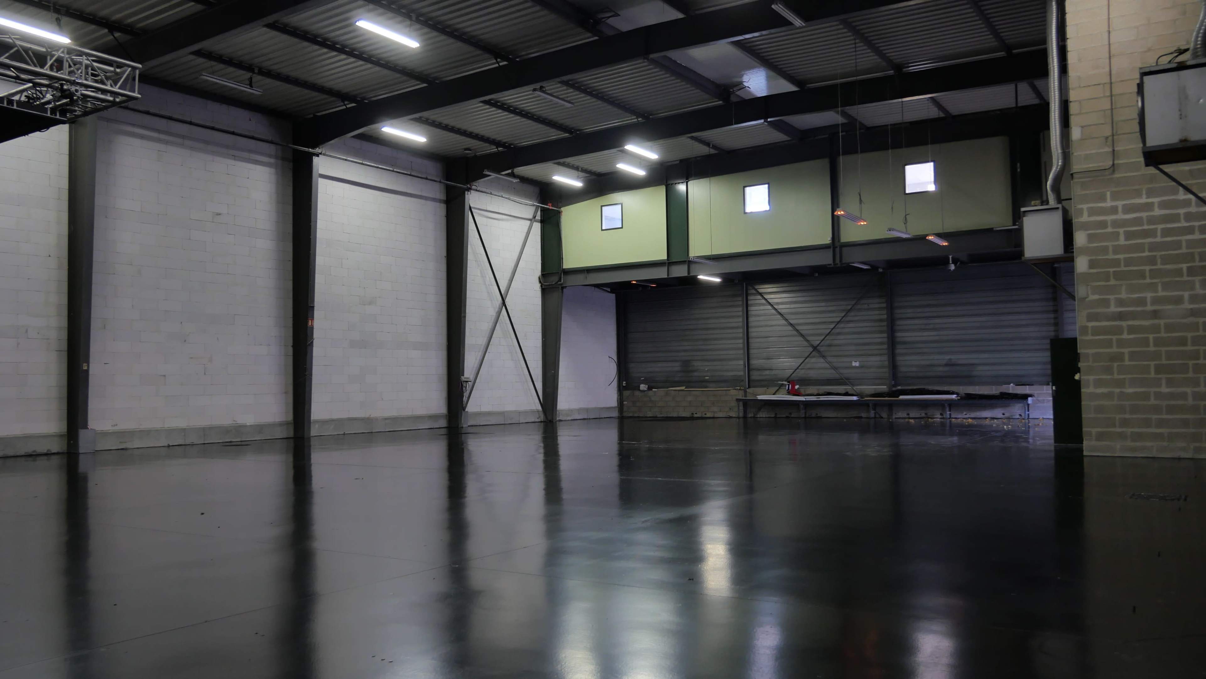 A spacious, industrial-style warehouse with polished concrete floors and white, gray, and green walls.