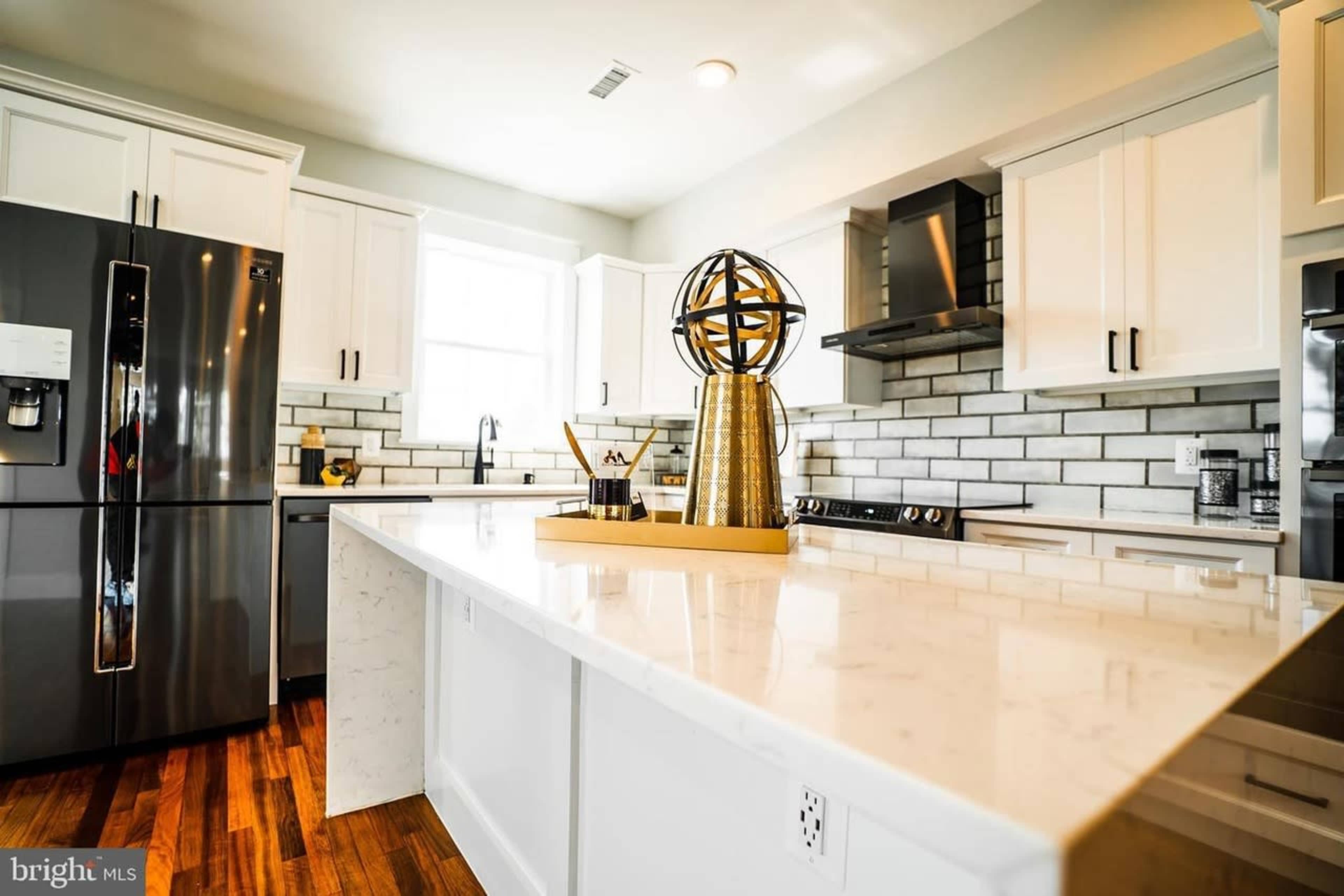The kitchen features stainless steel appliances, white cabinetry, and a large island with a decorative globe on top.
