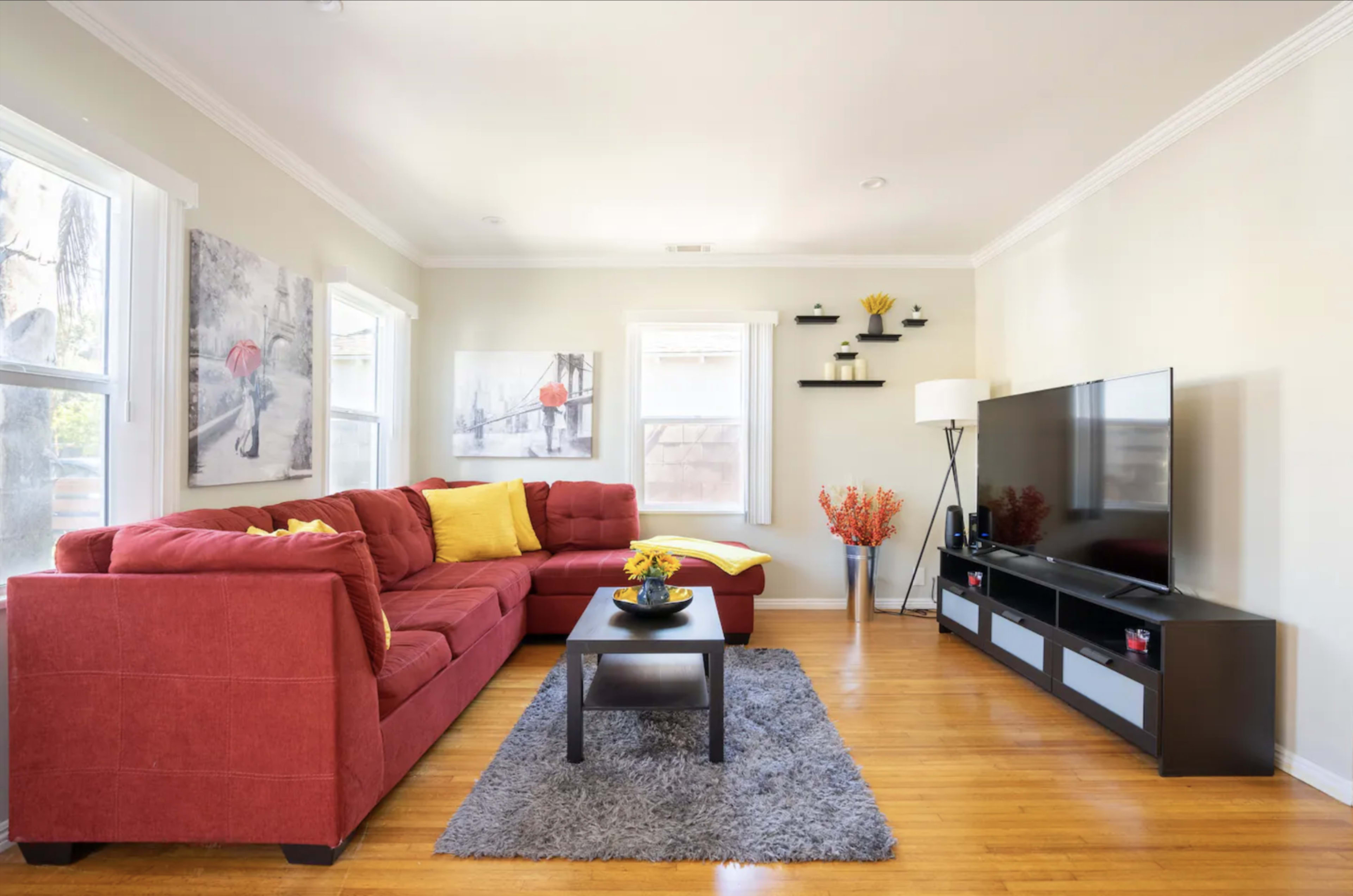 The image shows a modern living room with a red sectional sofa, a black coffee table, and a television on a low cabinet against the wall.
