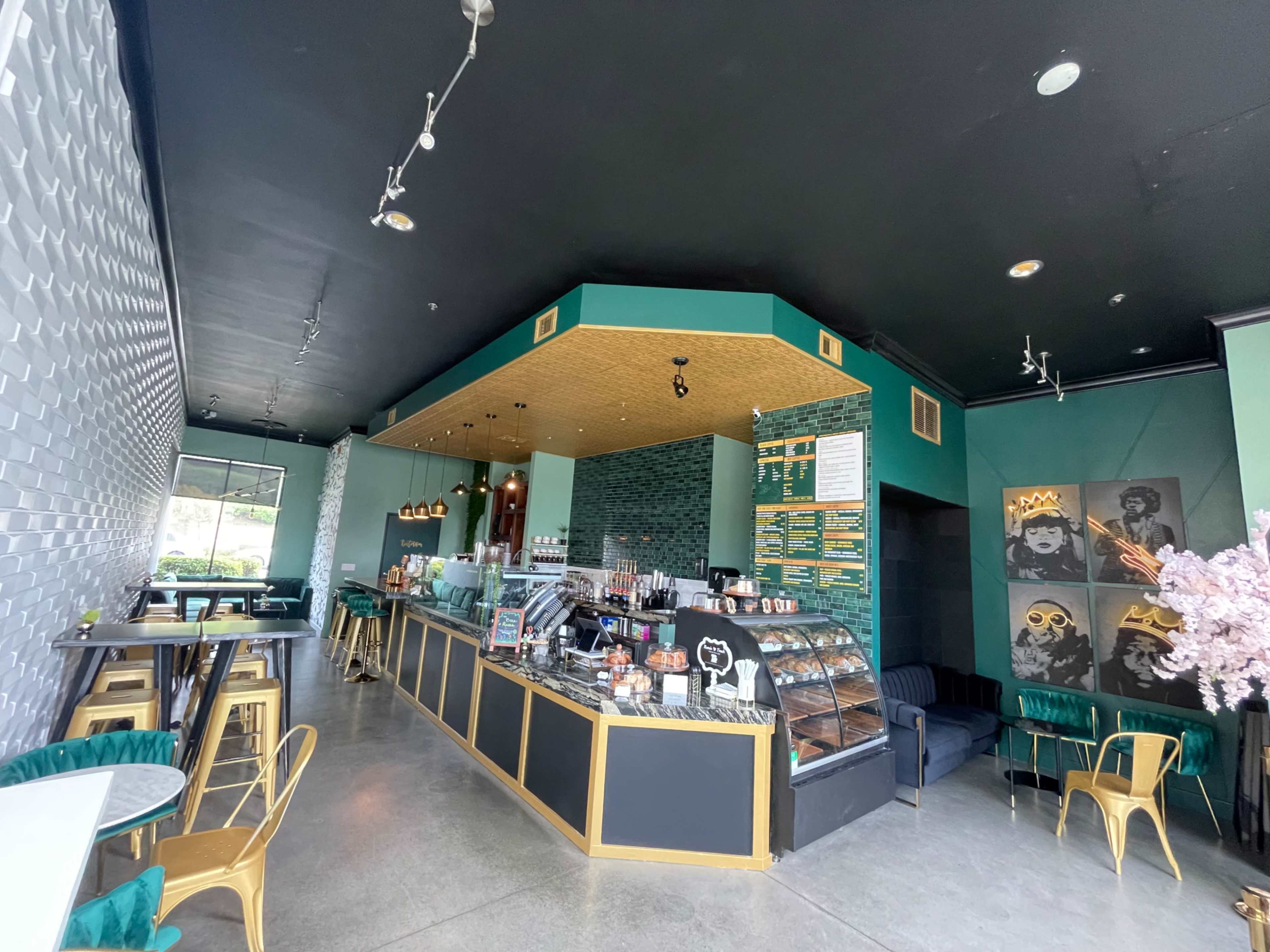The image shows a modern café interior with a service counter, seating areas, and decorative wall art.