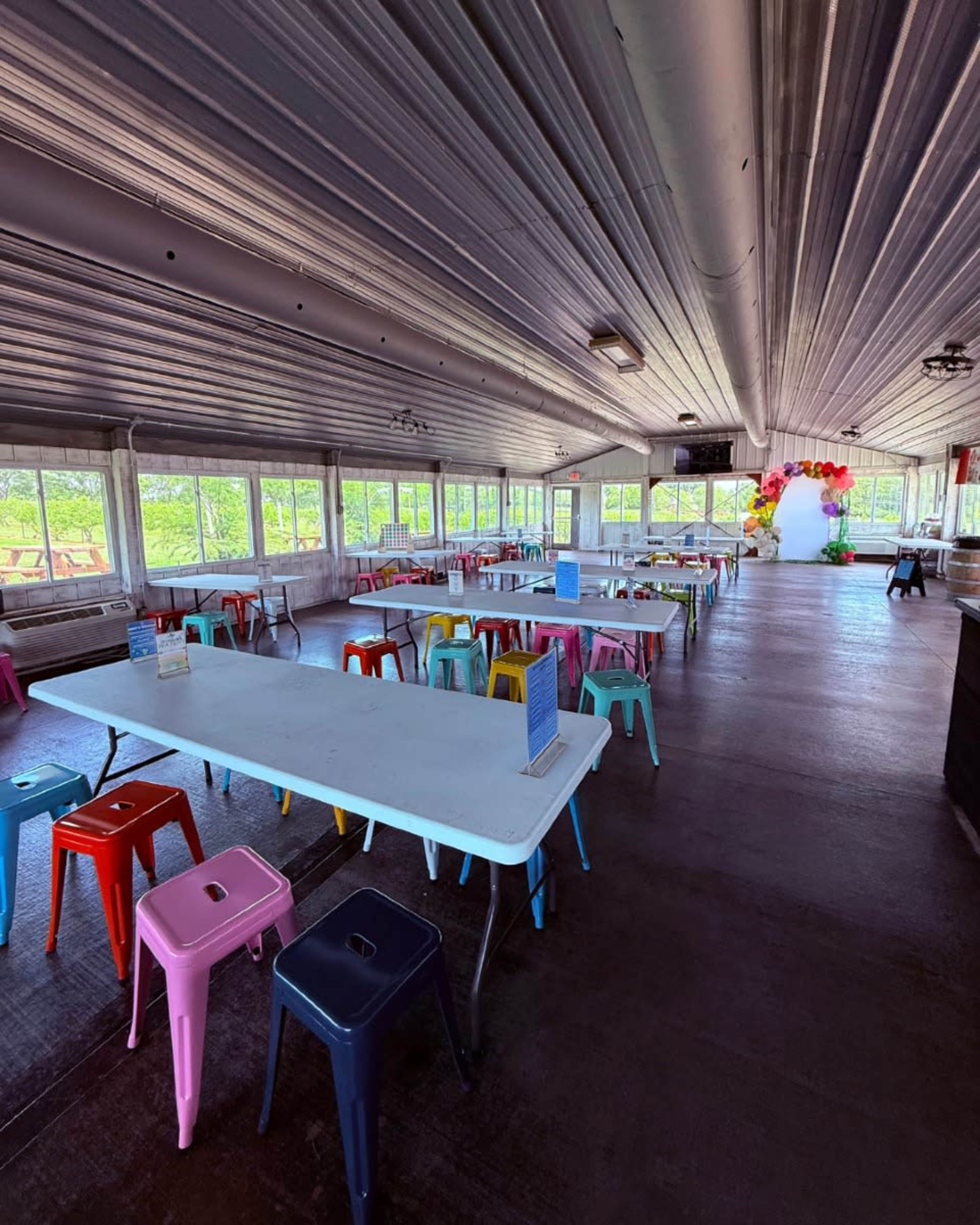 The image shows a spacious indoor area with multiple tables and colorful stools arranged for seating.