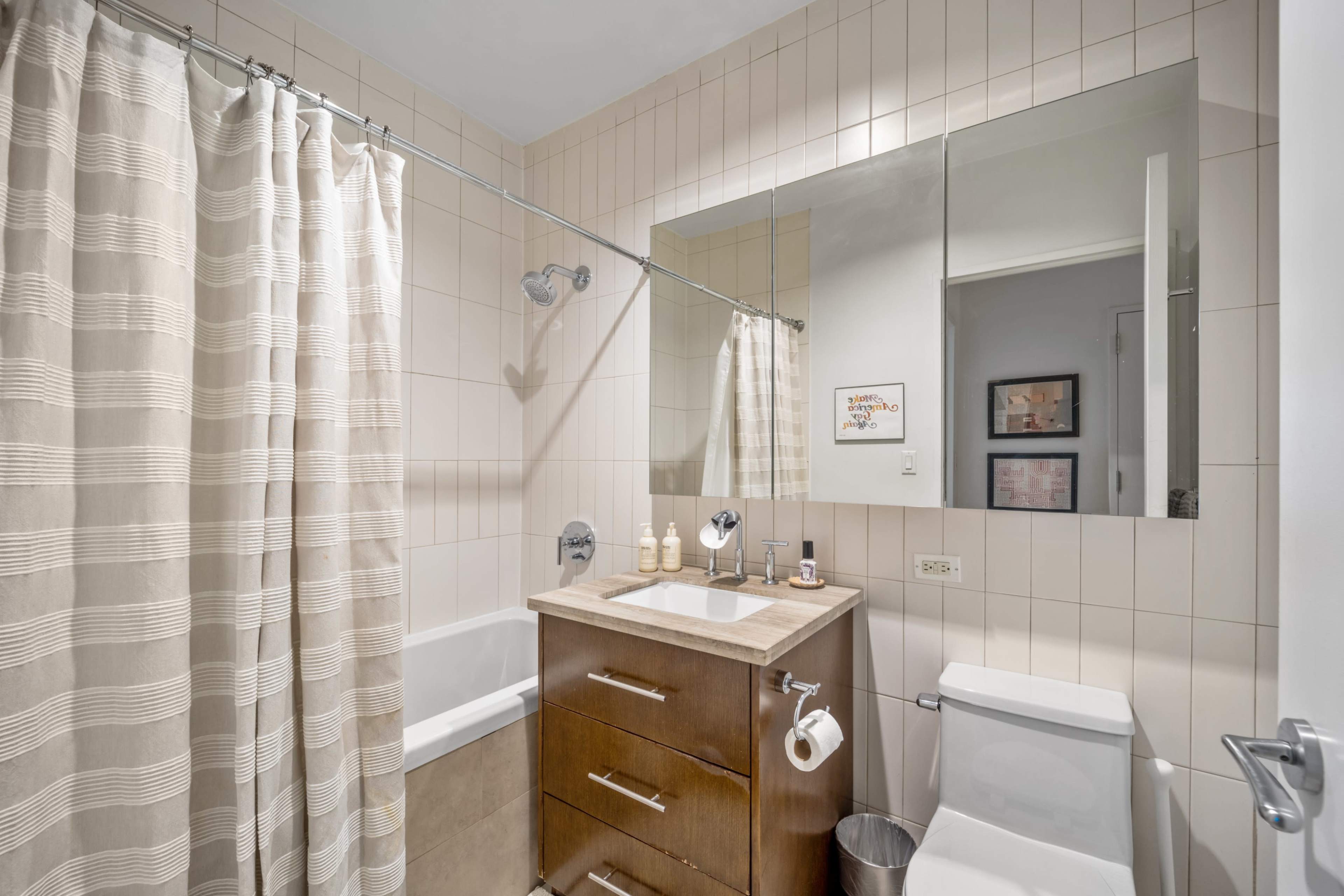 The image shows a bathroom with a bathtub, a washbasin with a stone counter, a mirror, and a shower curtain.
