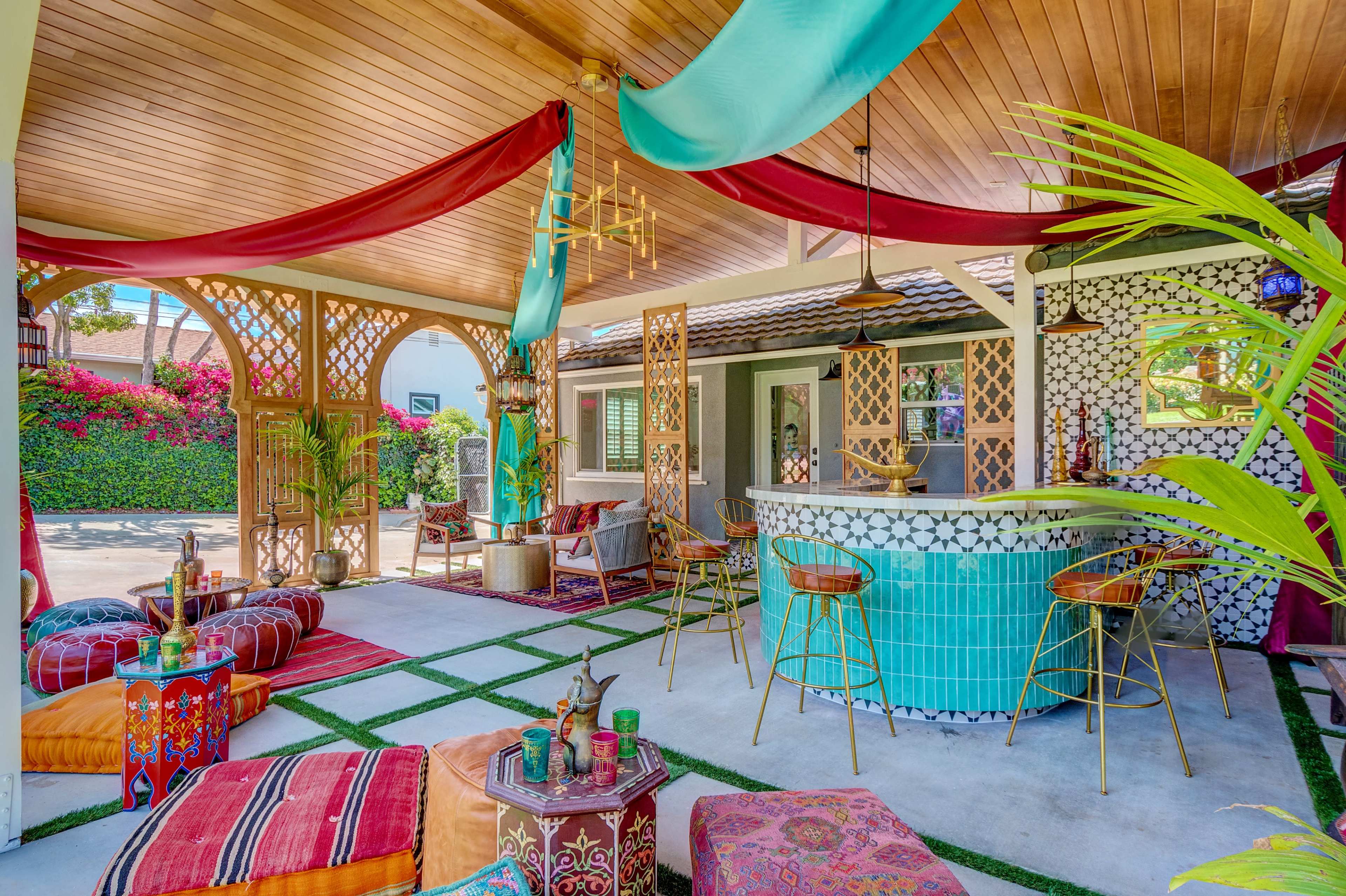 A vibrant outdoor lounge area with colorful textiles, a tiled bar, and lush greenery in the background.