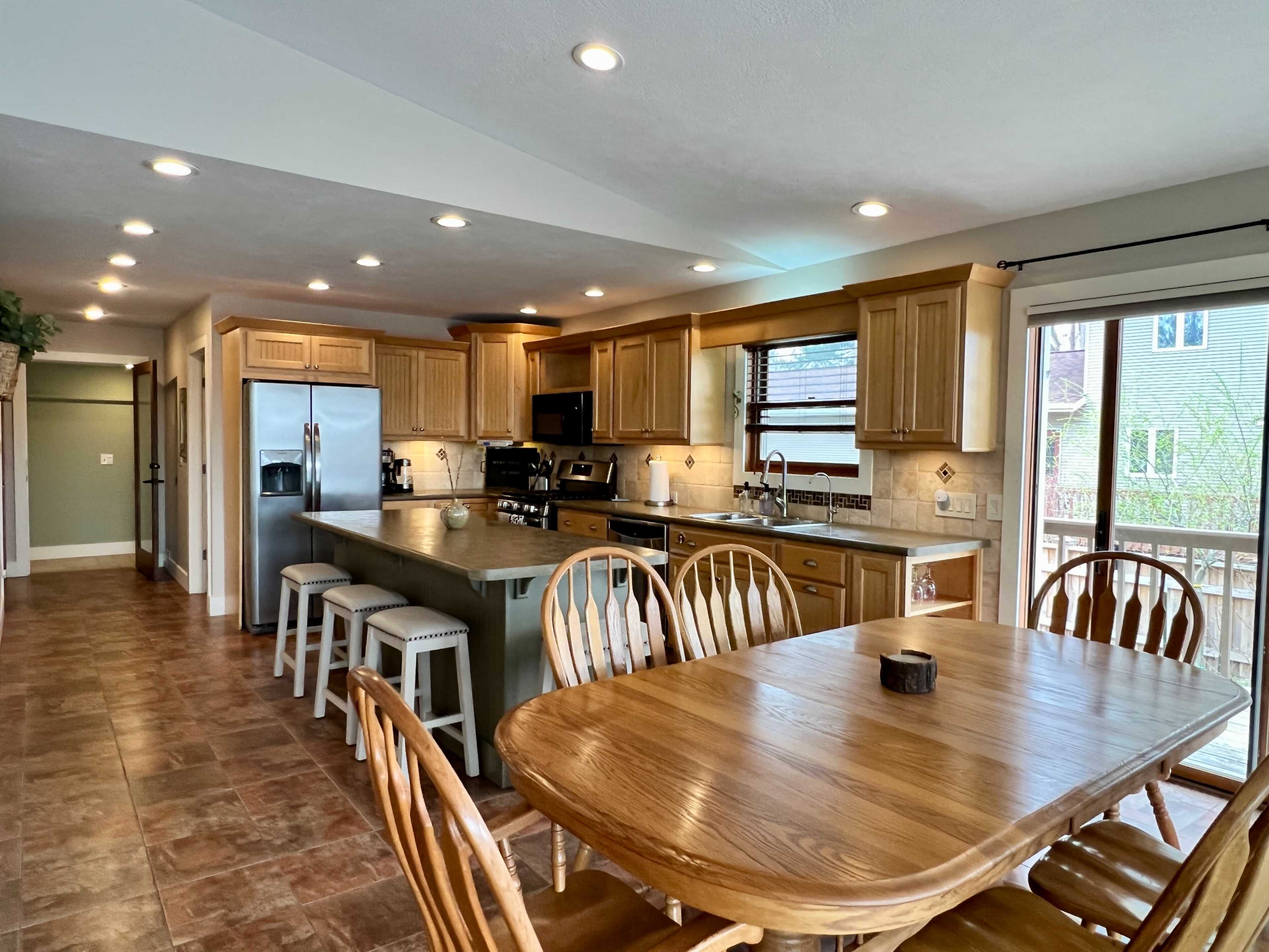 A spacious kitchen and dining area with wooden cabinetry, a large island, and a dining table surrounded by chairs.