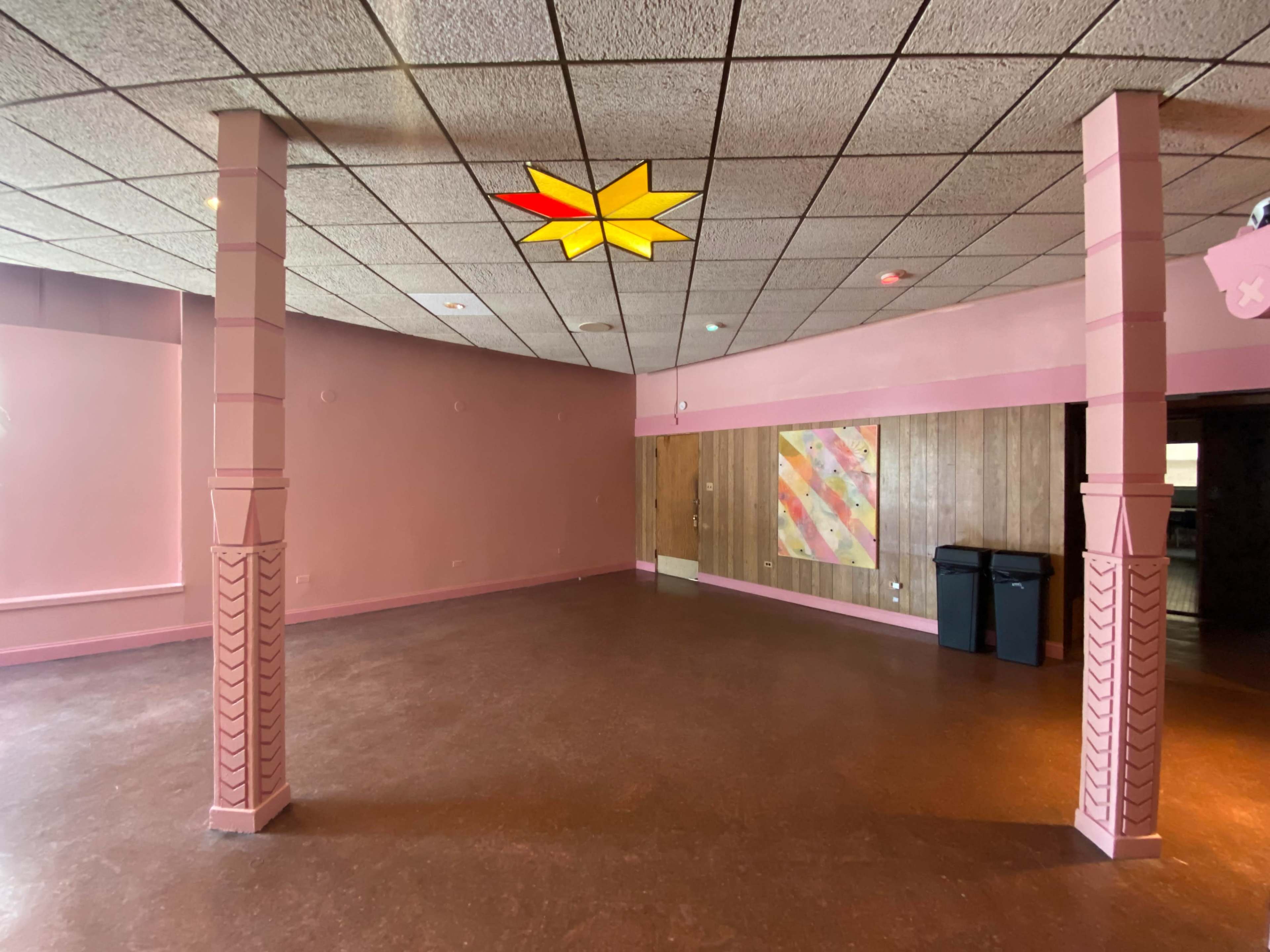 A pink-walled room with wooden accents, two decorative columns, and a ceiling light shaped like a star.