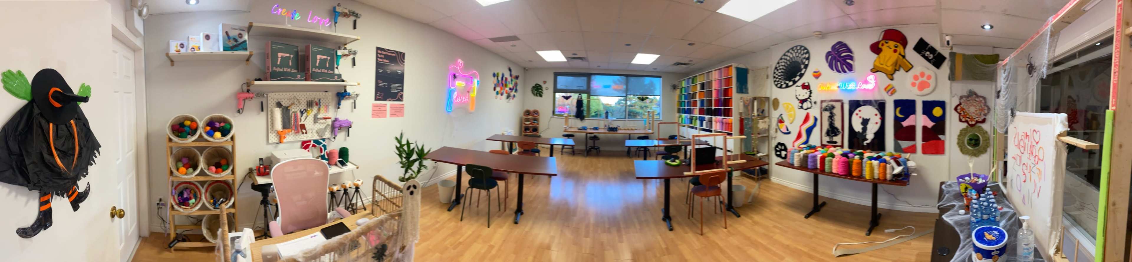 The image shows a brightly lit art studio featuring various tables, shelves with art supplies, and colorful wall decorations.