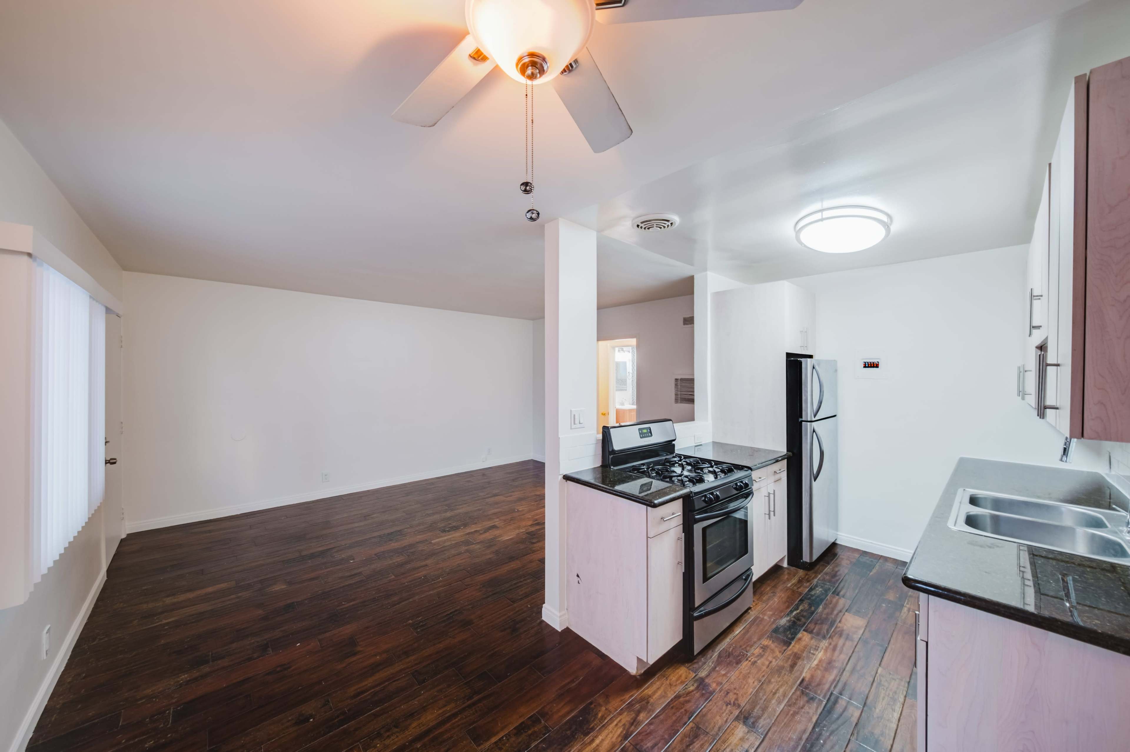 The image shows an open-concept kitchen and living area with hardwood floors and modern appliances.
