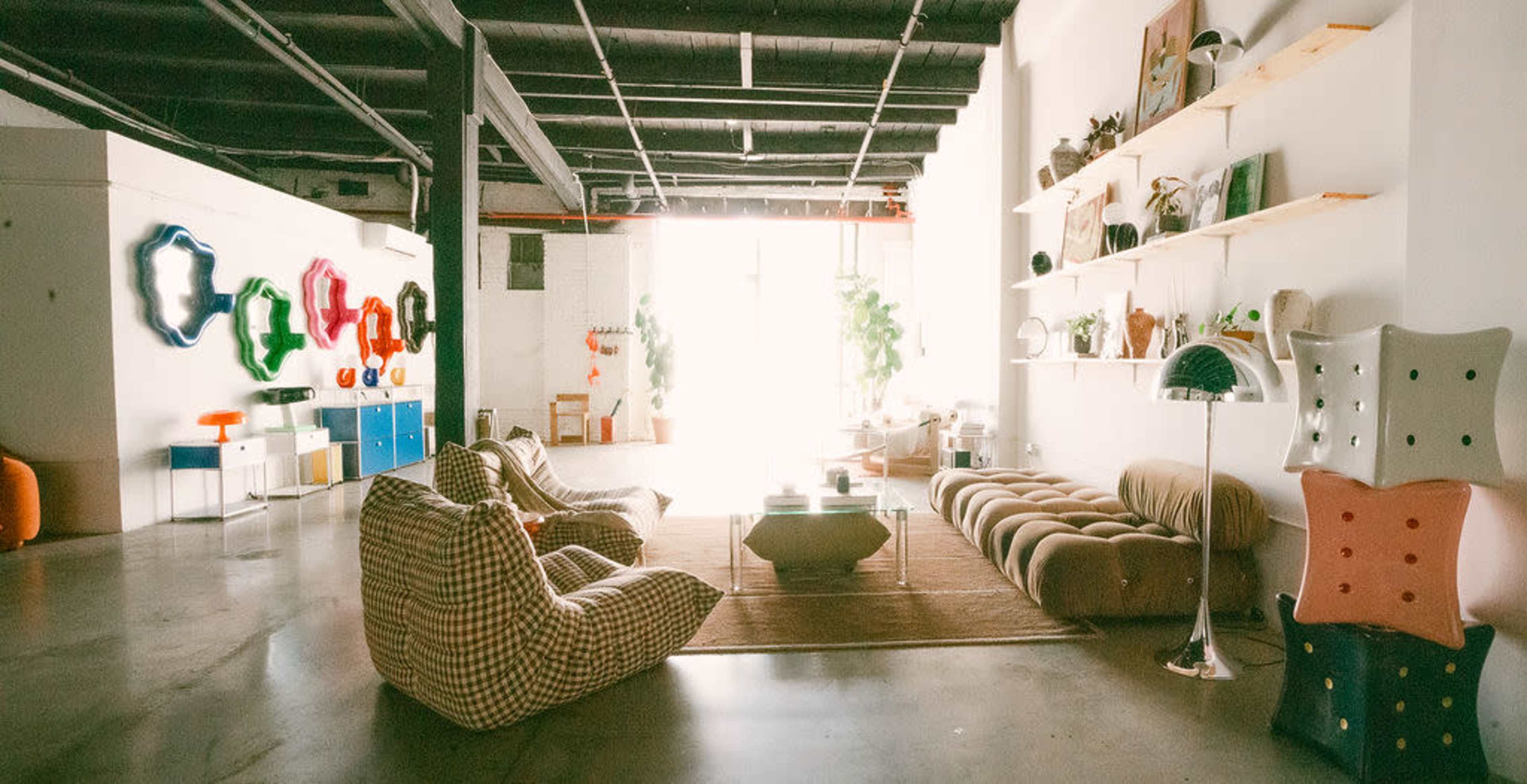 The image depicts a spacious, modern interior with various furniture pieces, including bean bags, a curved sofa, and shelves displaying decorative items.