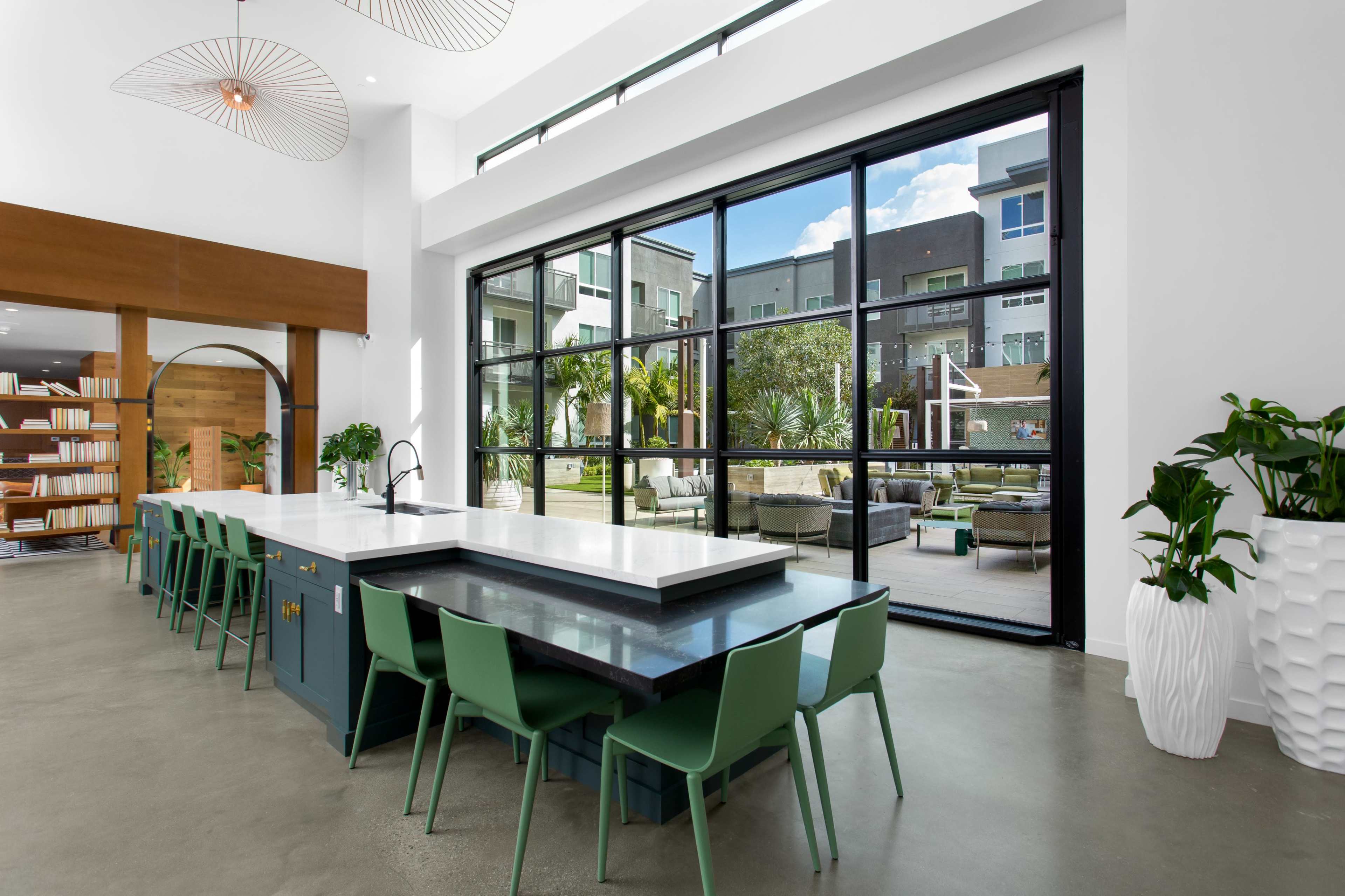 A modern kitchen features a large island with seating, overlooking a spacious outdoor area through expansive glass doors.