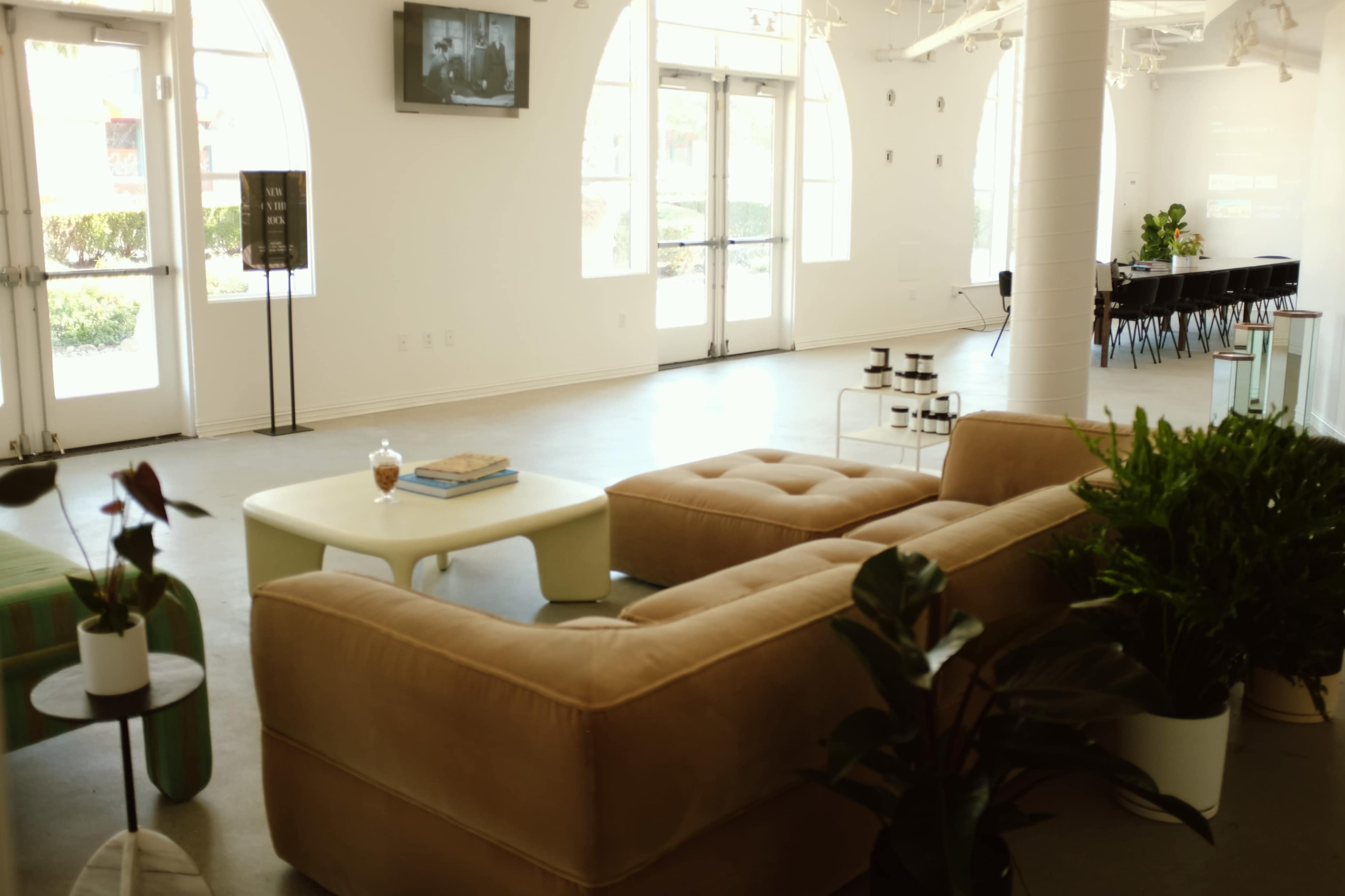 A spacious, minimalist room with a beige sectional sofa, a small coffee table, and large windows letting in natural light.