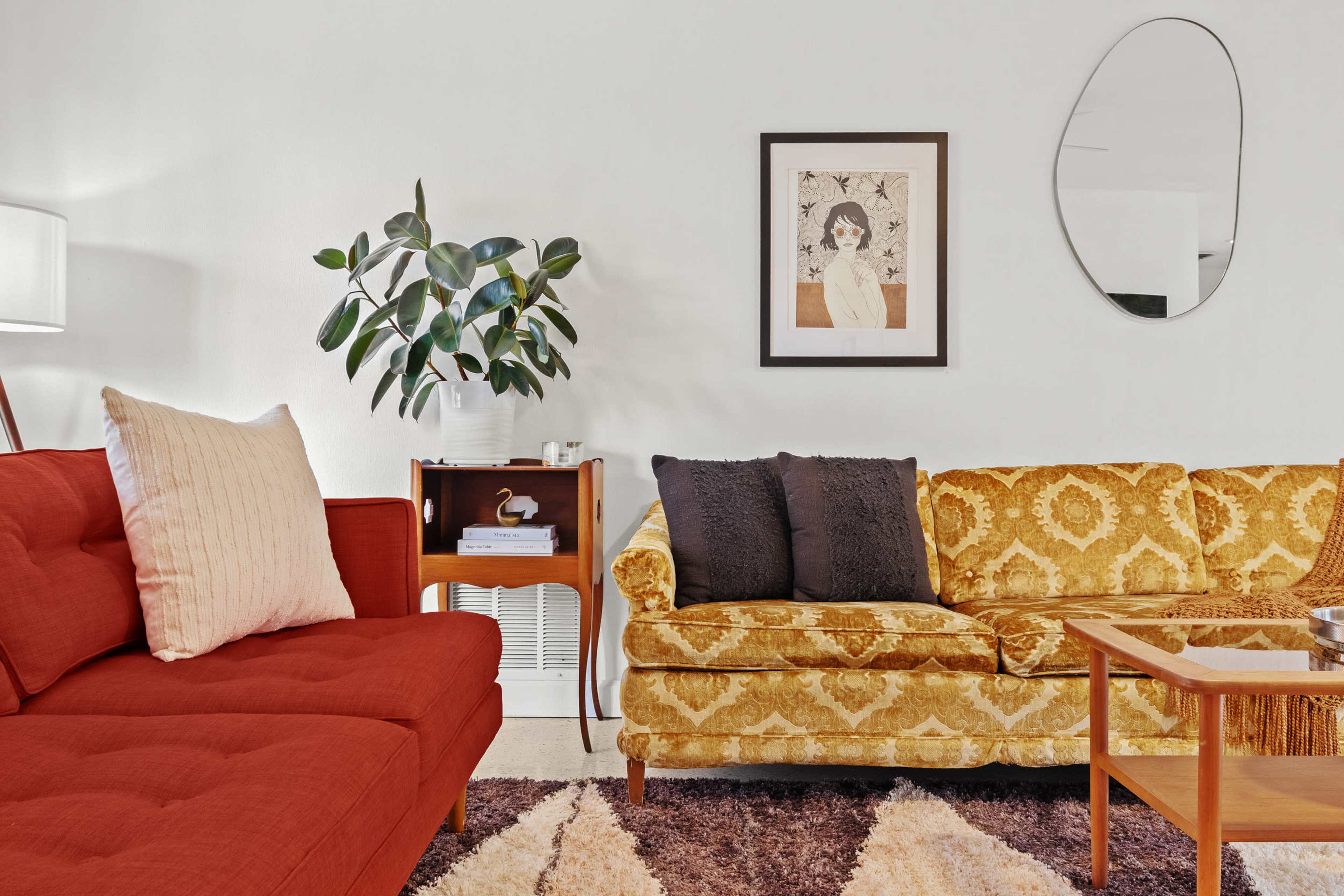 The scene features a living room with a red couch, a yellow patterned sofa, a potted plant, a framed artwork on the wall, and a coffee table.