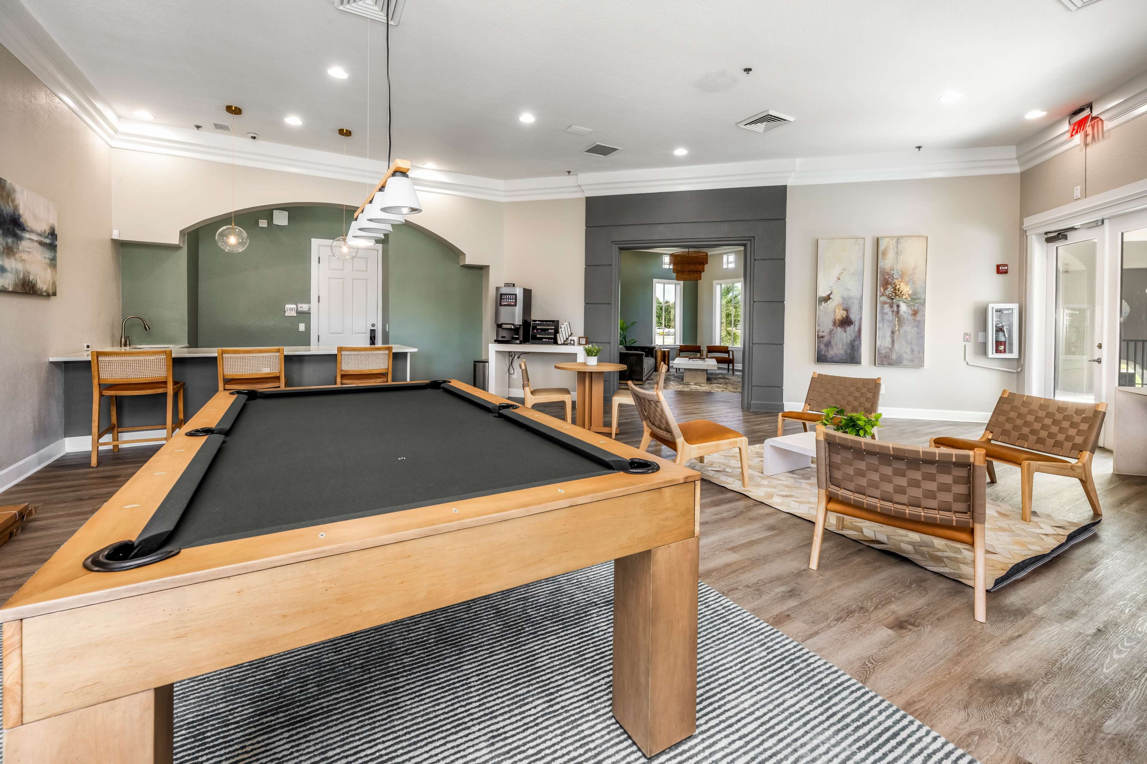 The image shows a communal lounge area with a pool table, seating arrangements, and modern decor.