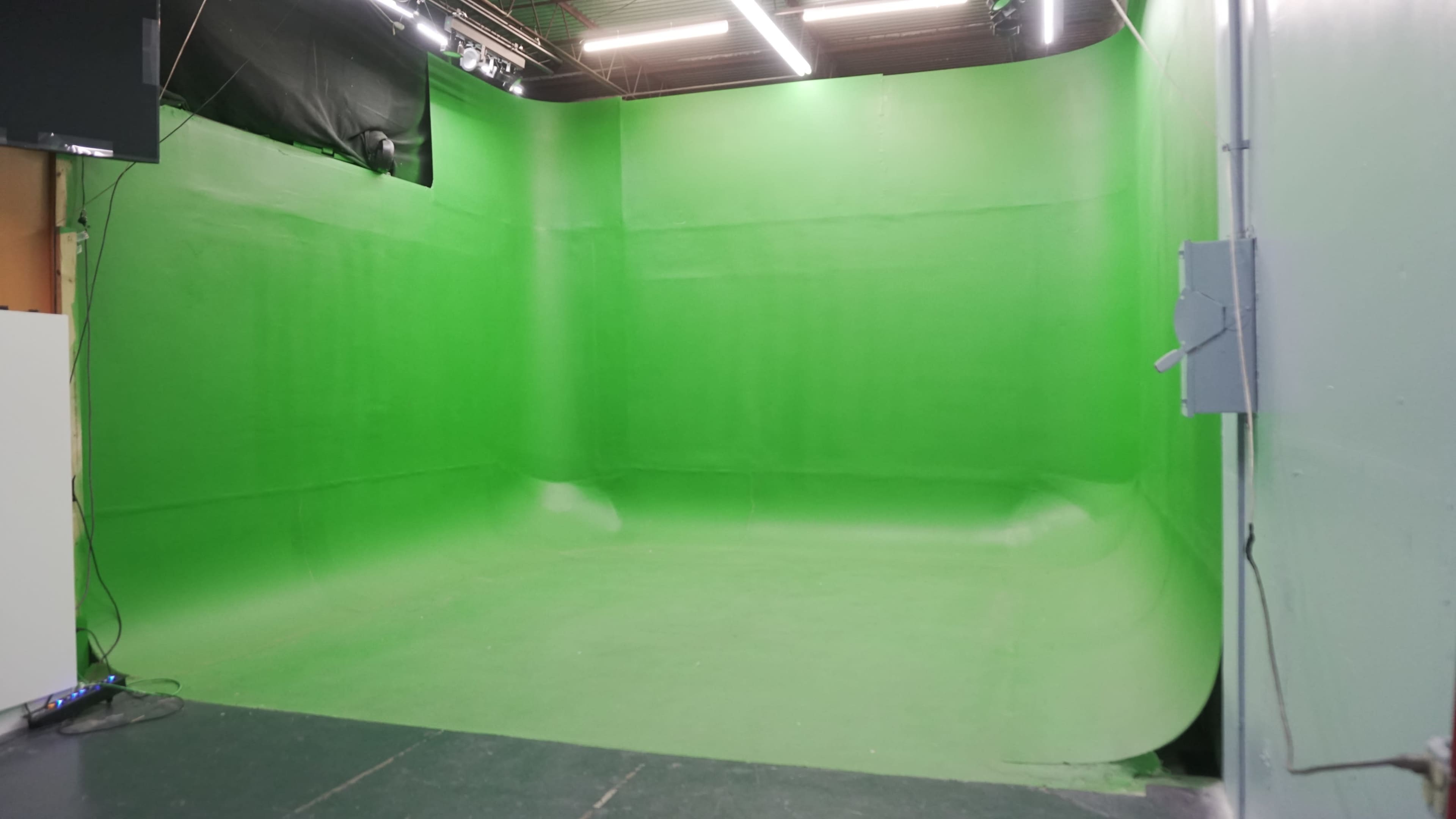 The image shows a large green screen studio with flat walls and a seamless floor.