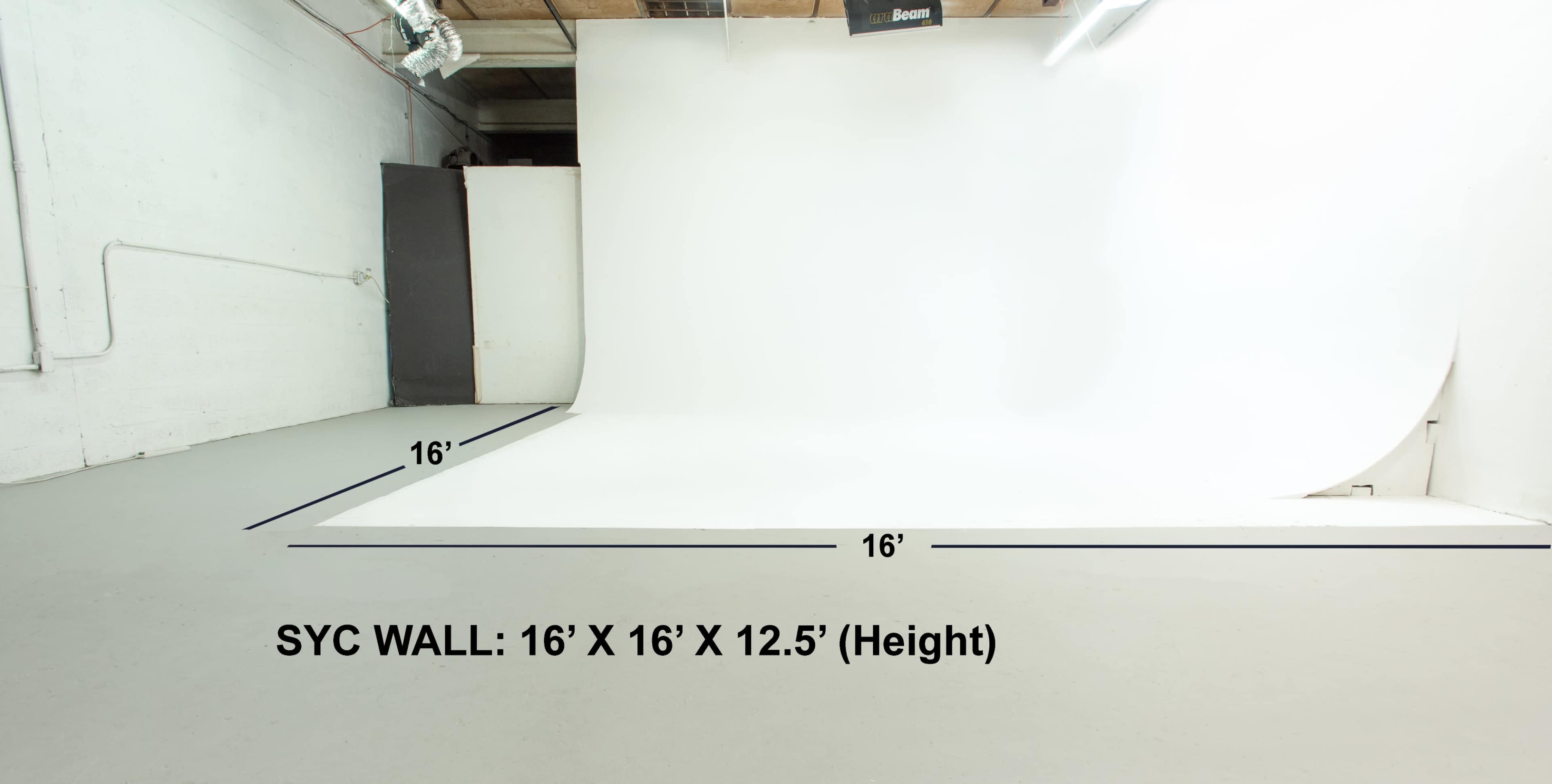 The image shows a photography studio featuring a white cyc wall measuring 16 feet by 16 feet, with a height of 12.5 feet.