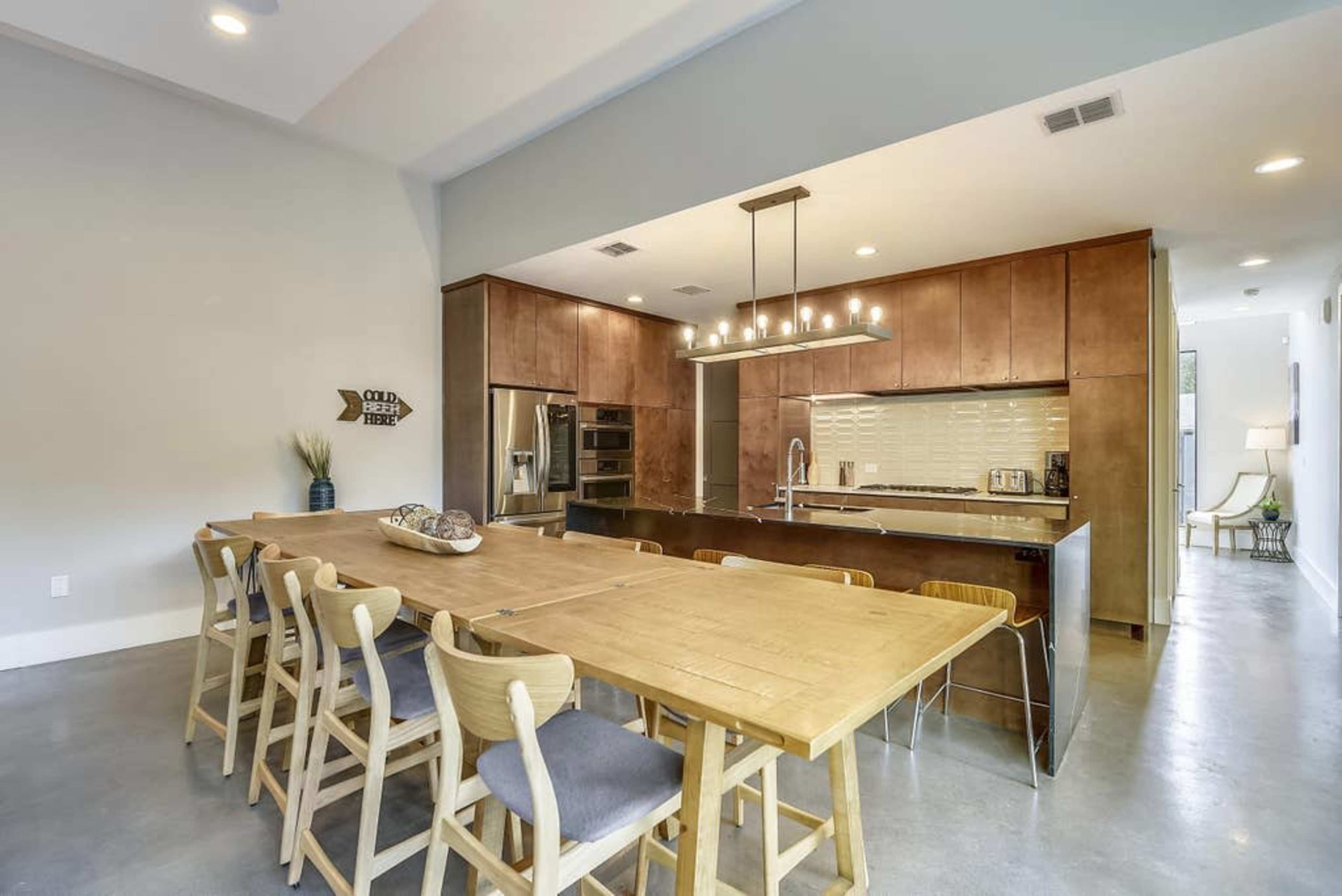 A modern kitchen and dining area with a large wooden table and contemporary cabinetry.