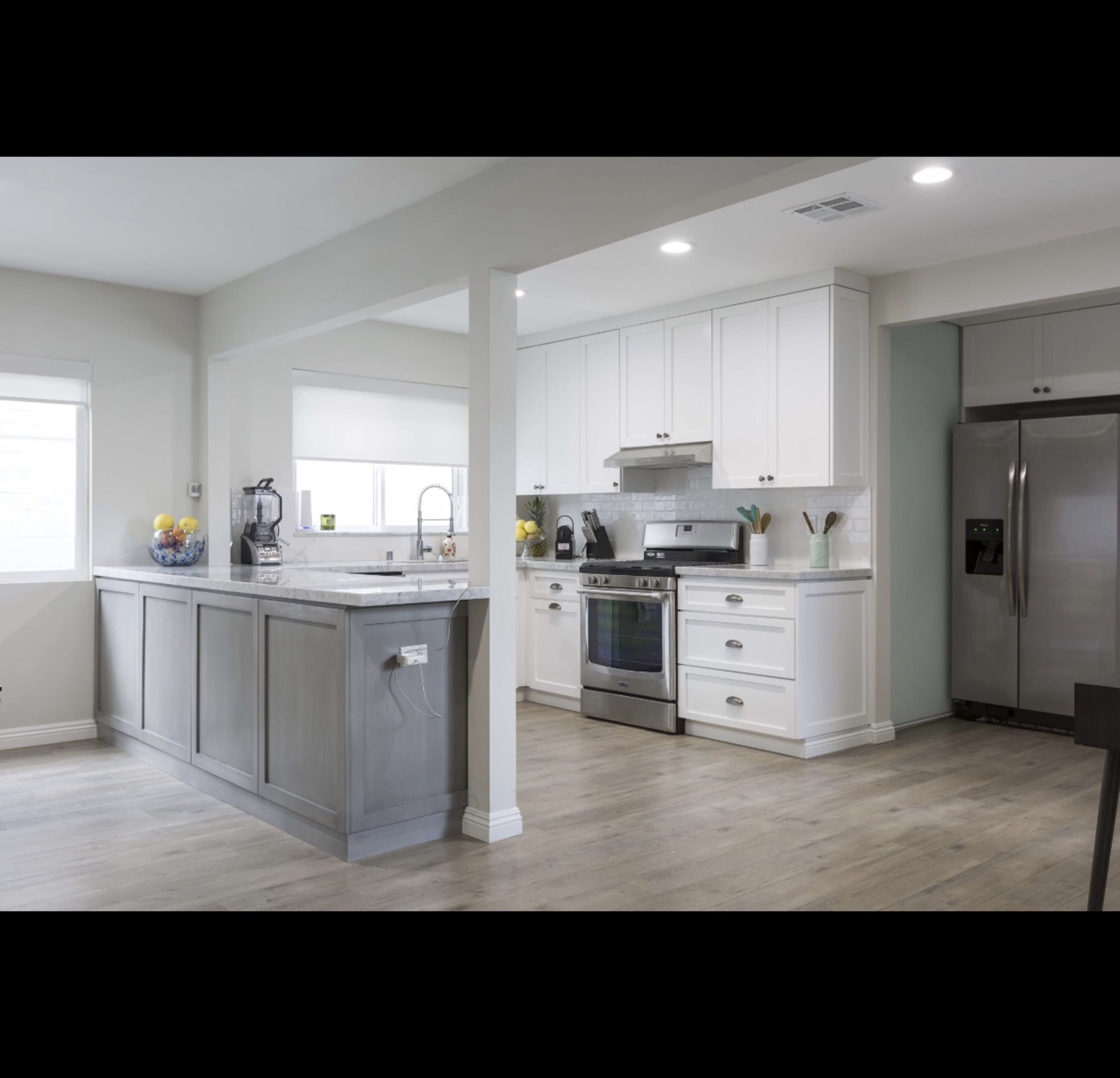 A modern kitchen with white cabinetry, stainless steel appliances, and a wood-finish island.