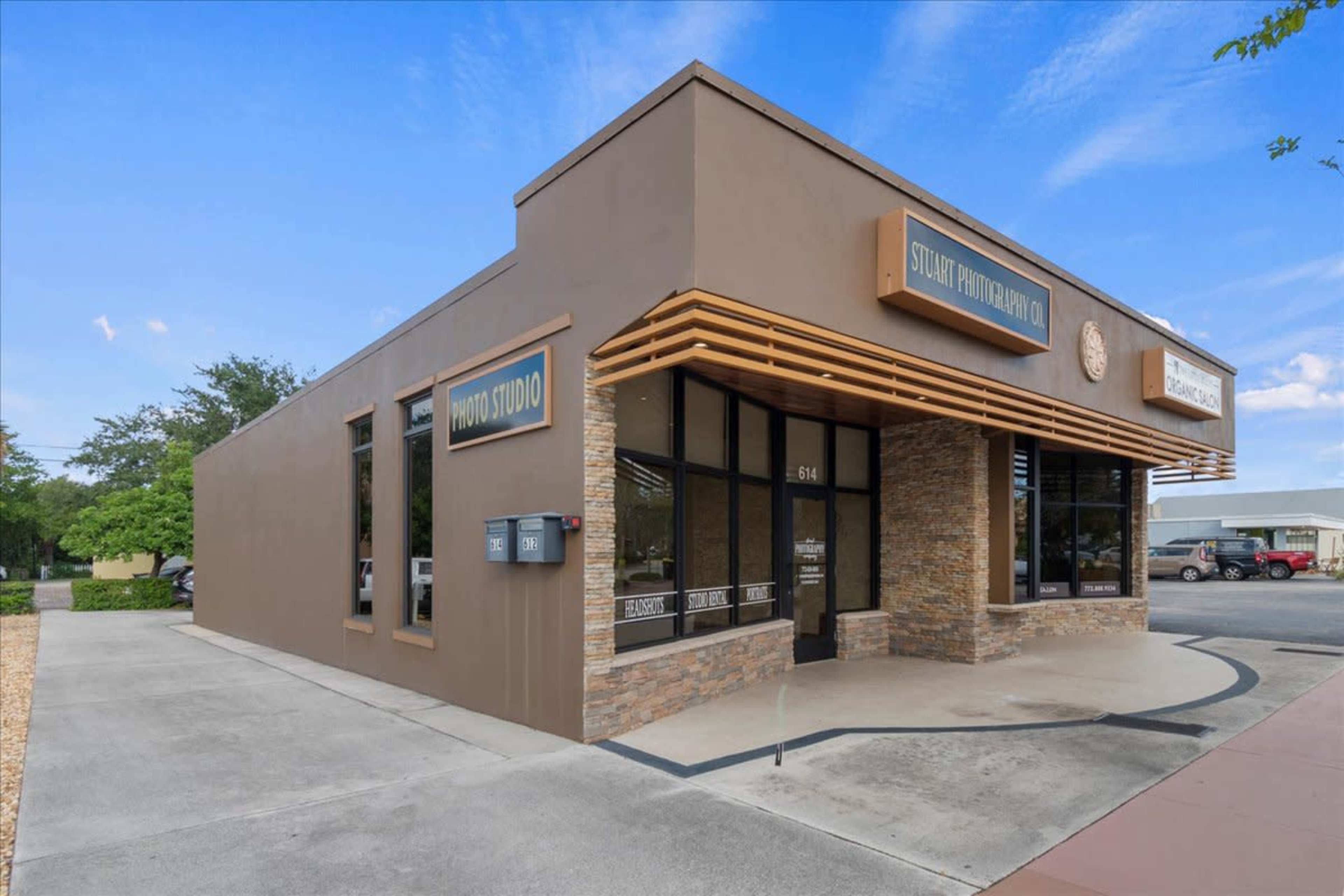 A modern photo studio building with a stone and brown exterior, featuring large windows and decorative signage.