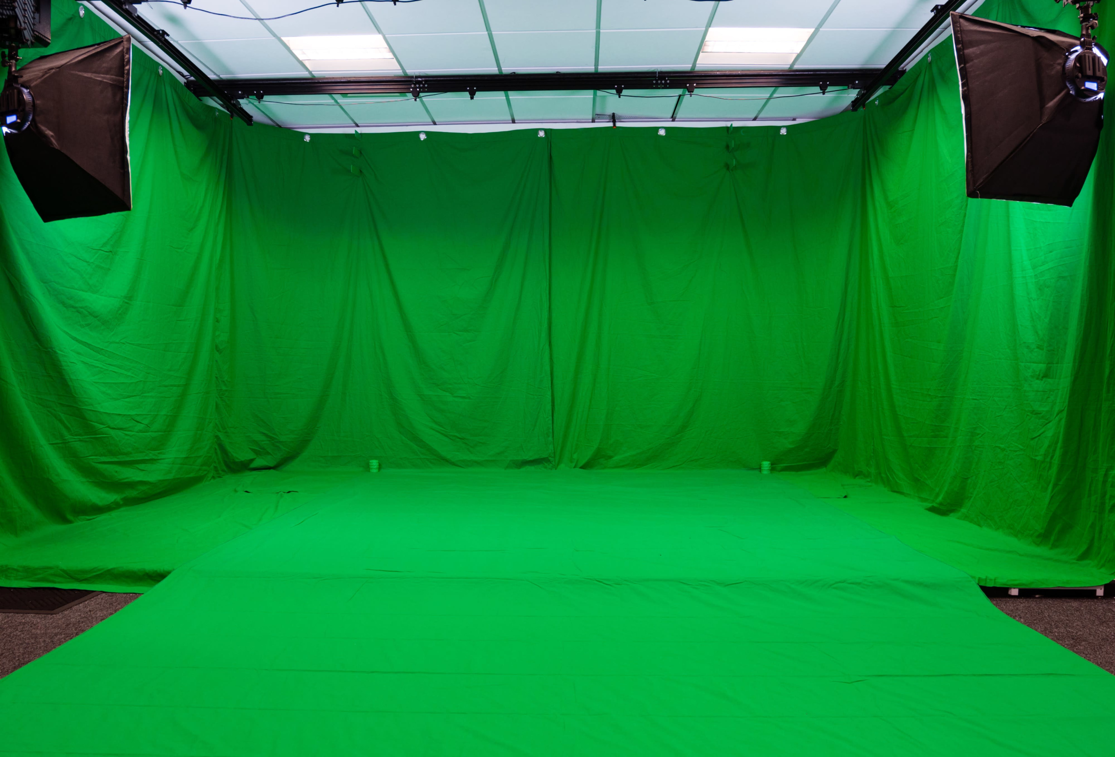 A room filled with green fabric draped on the walls and floor, set up for green screen filming.