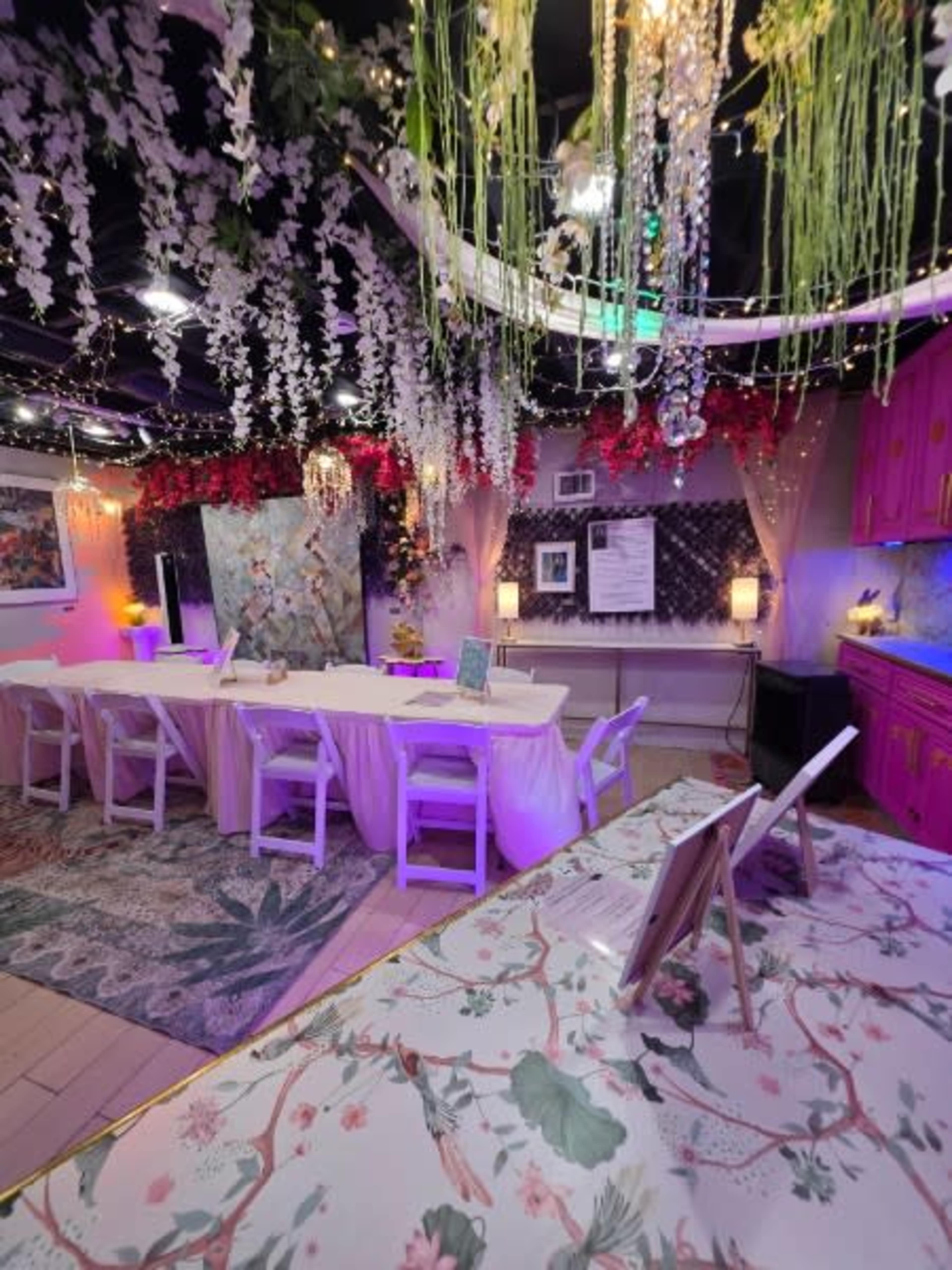 The image shows an elegantly decorated event space with a long table, floral arrangements, and ambient lighting.