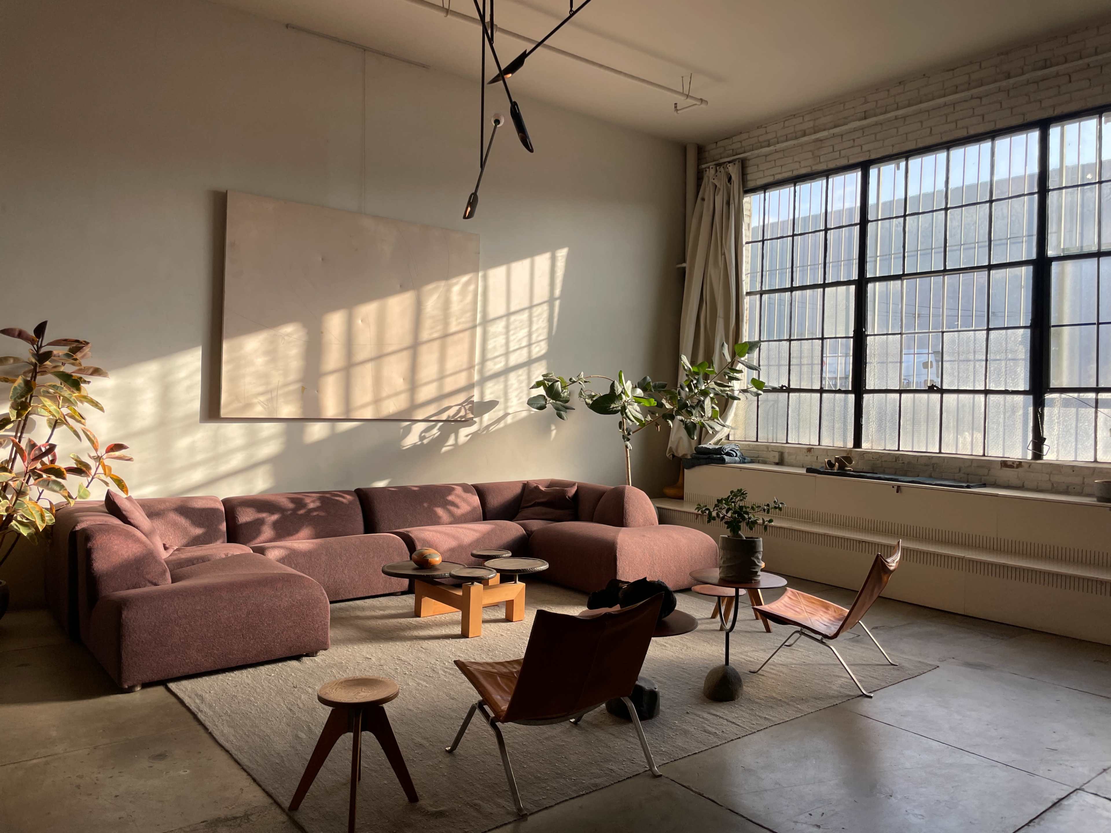 A spacious living room features a large, U-shaped sofa, two wooden chairs, a coffee table, and large windows that let in natural light.