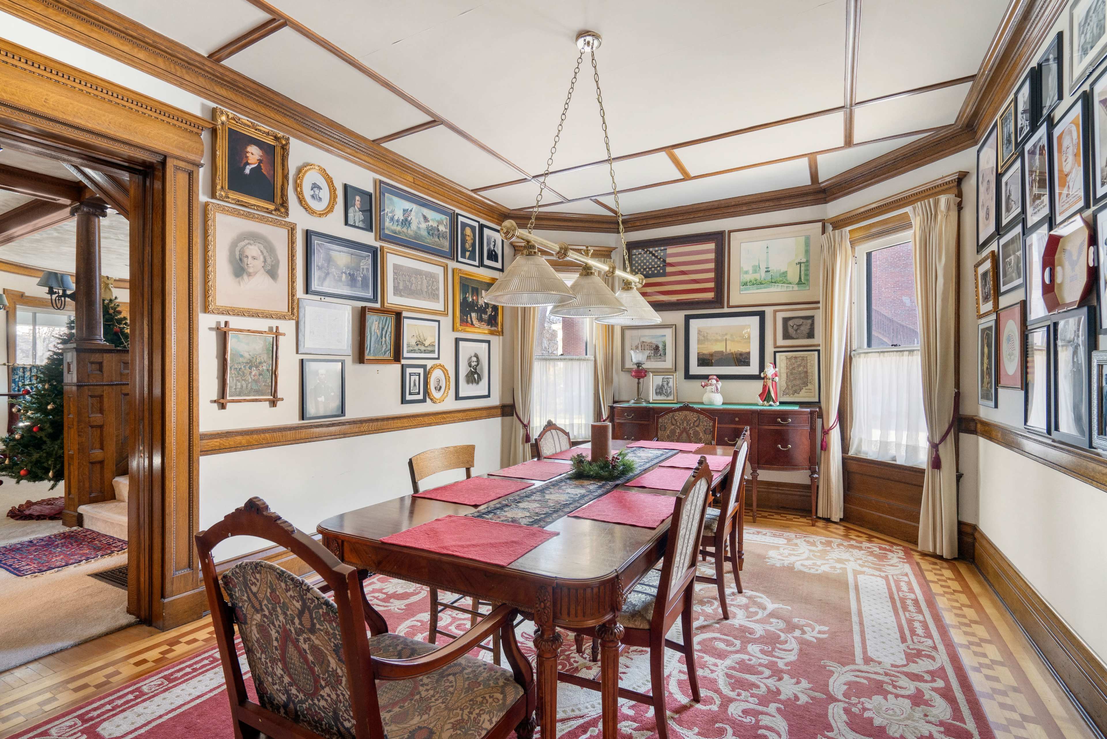 A dining room featuring a wooden table surrounded by chairs, with a variety of framed artwork and photographs lining the walls.