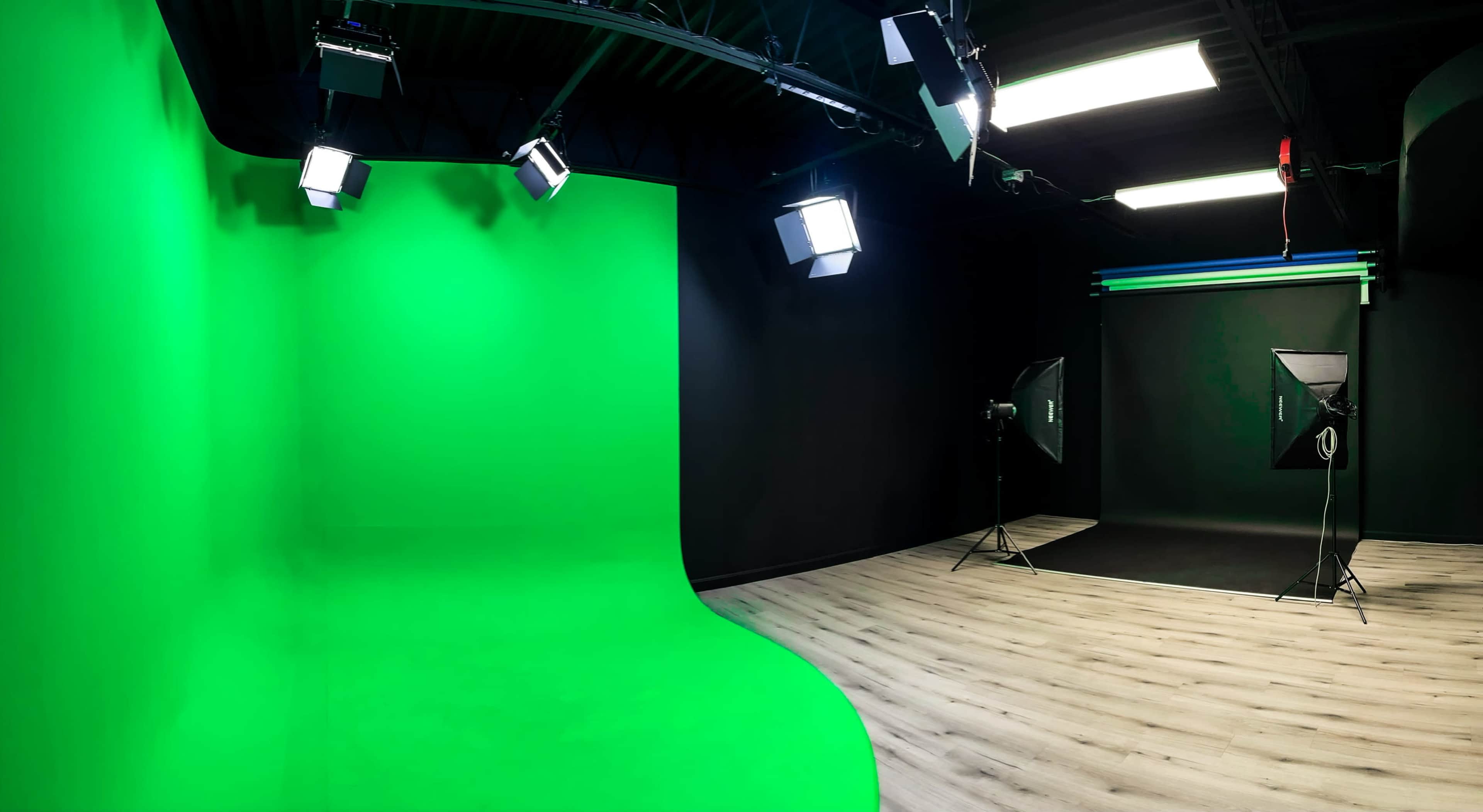 A photography studio with a green backdrop, spotlights, and a black floor.