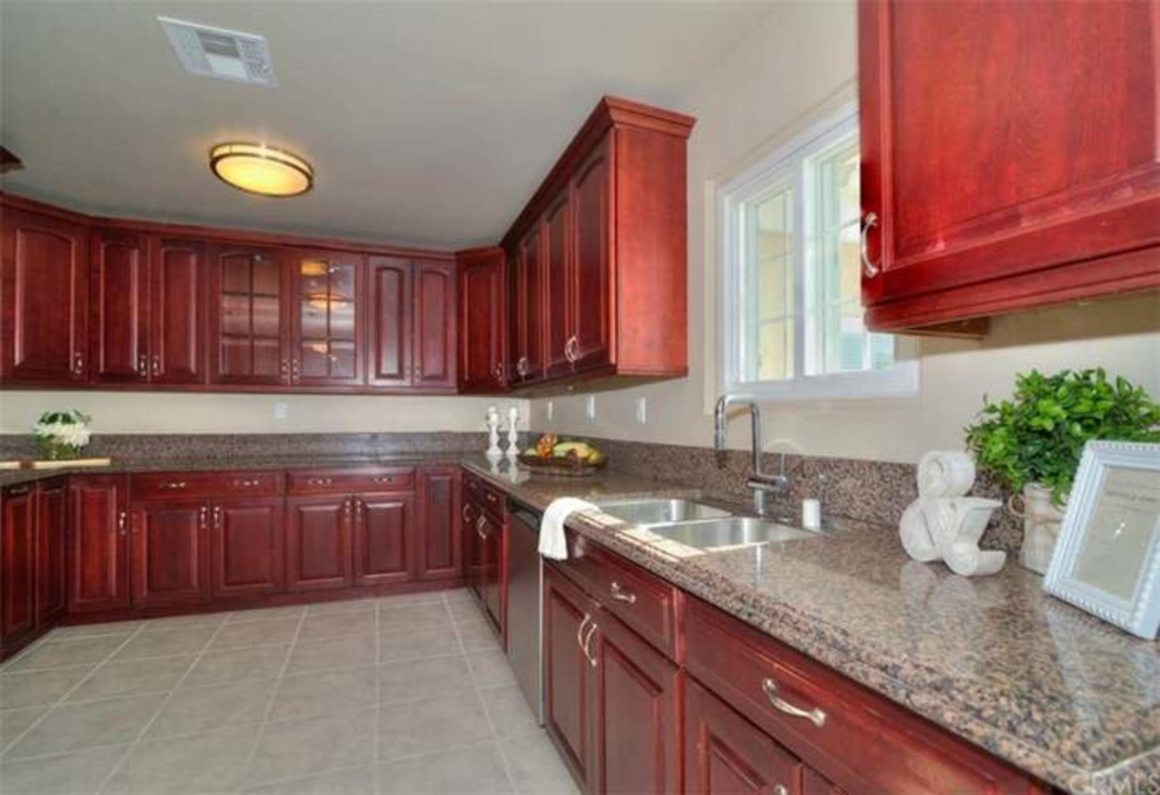 The image shows a kitchen featuring dark wood cabinetry, a granite countertop, and a window above the sink.